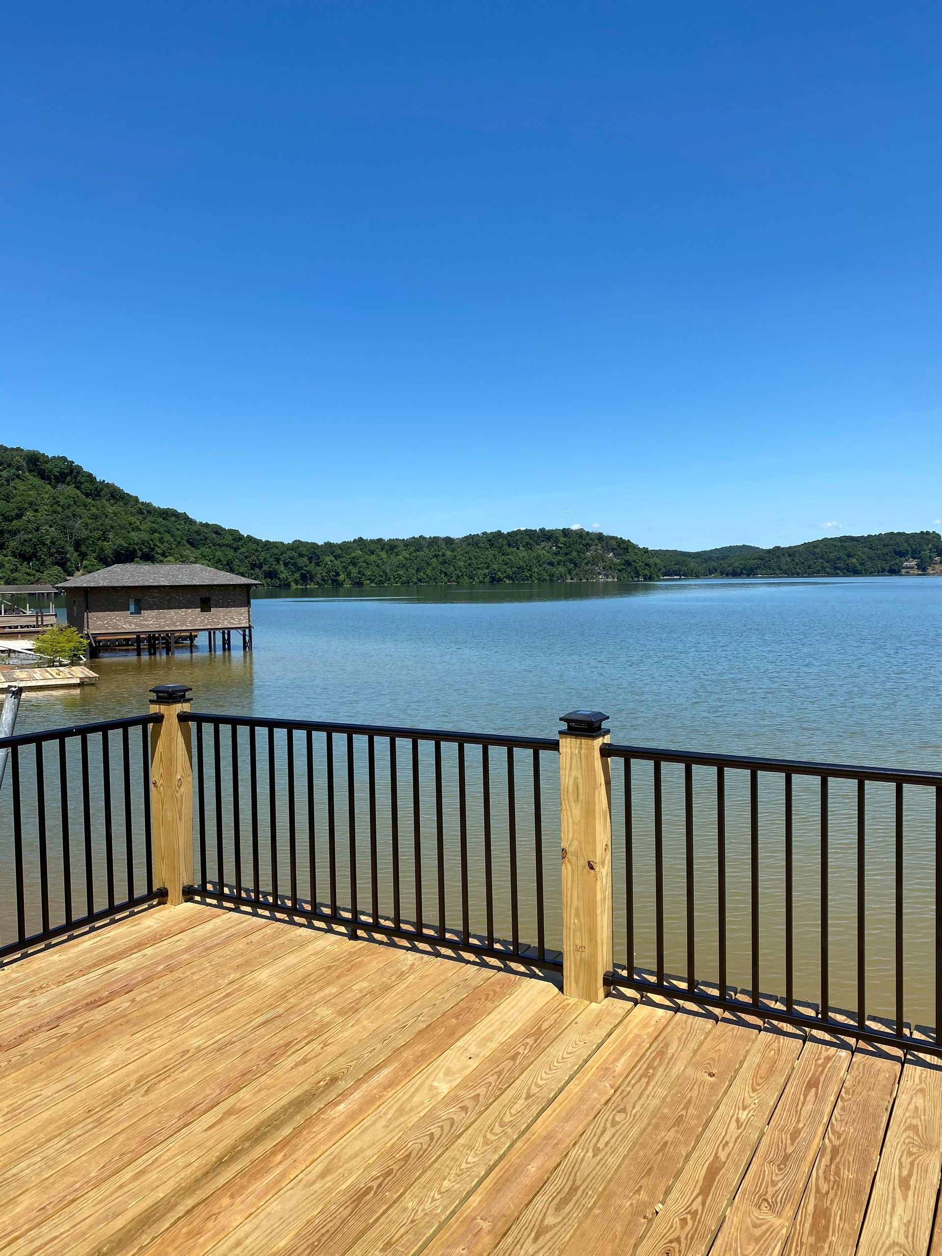 A wooden deck with a metal railing overlooking a lake.