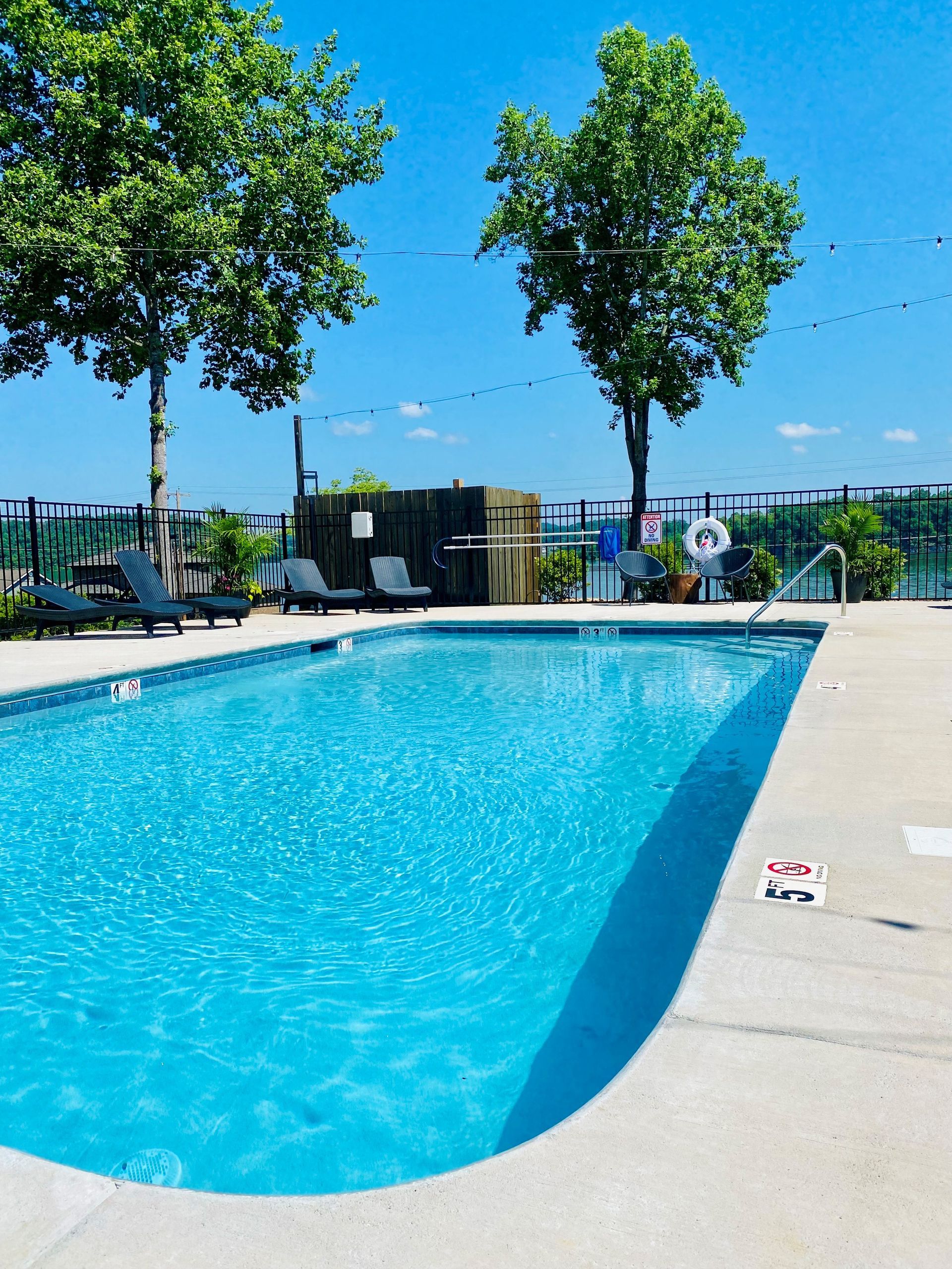 A large swimming pool surrounded by chairs and trees