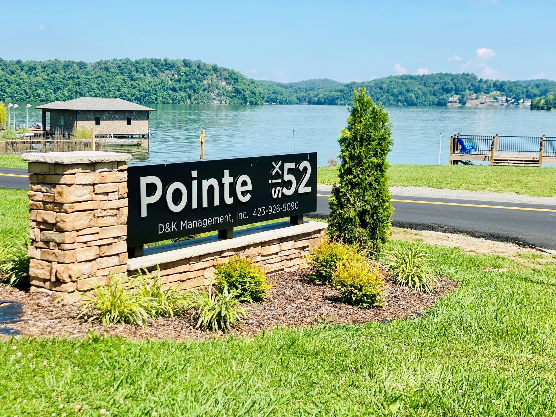 A sign for pointe 52 is sitting in the grass next to a lake.