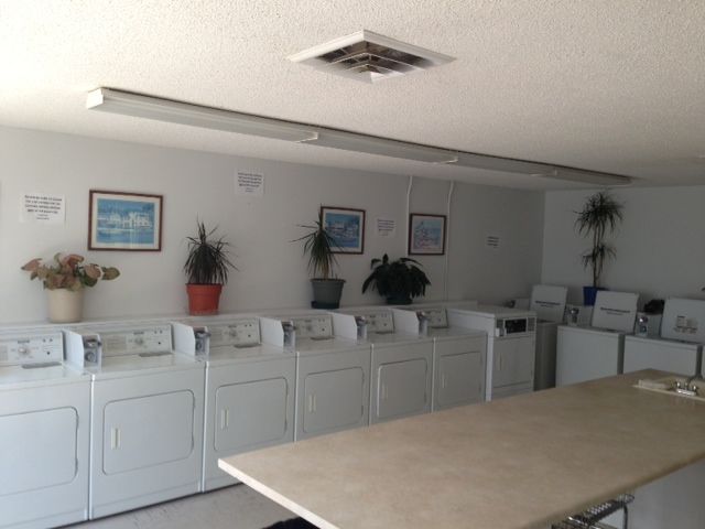 A laundromat with white washers and dryers and a table