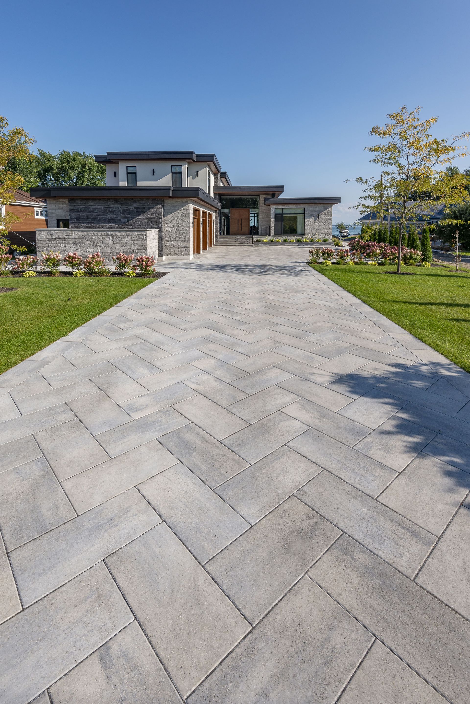 Une allée menant à une grande maison avec un motif à chevrons.