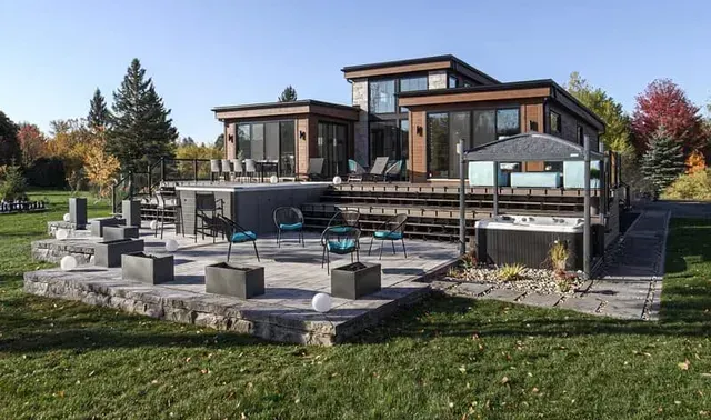 Une grande maison avec un patio et un jacuzzi devant.