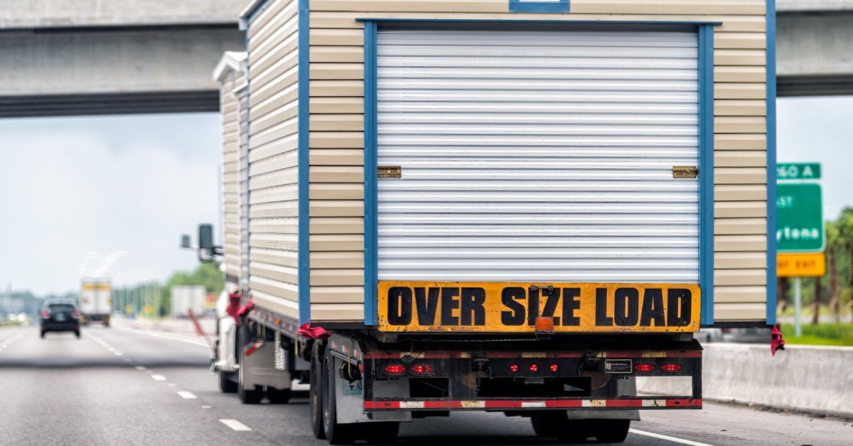 A hauler truck travels down the interstate with a tiny home that has an 