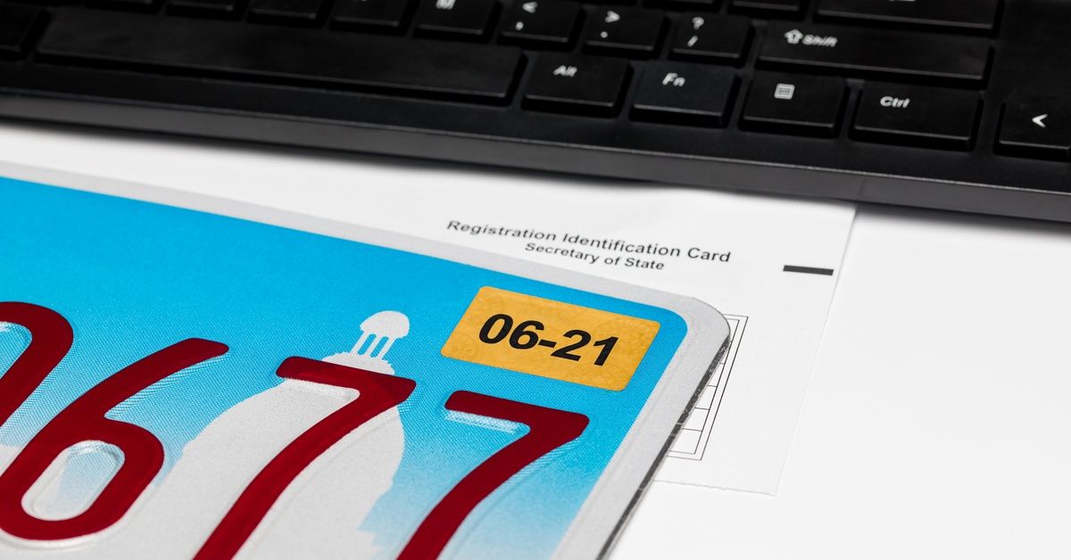 A white paper marked “Registration Identification Card” resting underneath a license plate and keyboard.