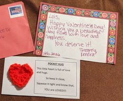 Valentine's Day card and crocheted heart. Red envelope and handwritten note wishing Lois a happy day, with a 