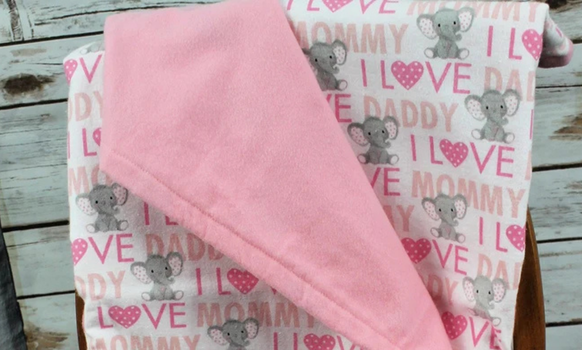Pink and white baby blanket with elephants, hearts, and text 
