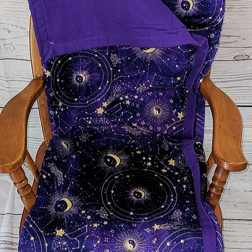 A purple celestial blanket draped over a wooden rocking chair.
