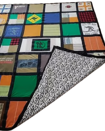 T-shirt quilt, multicolored squares stitched together, with black border and patterned backing, angled perspective.