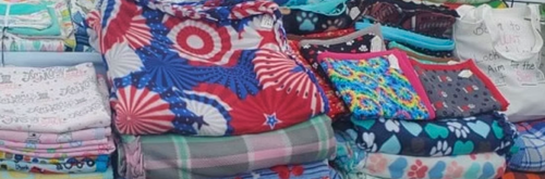 Stacks of colorful patterned fabrics in a display, including patriotic designs and paw prints.