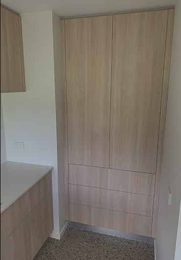 A kitchen with wooden cabinets and drawers and a white counter top.