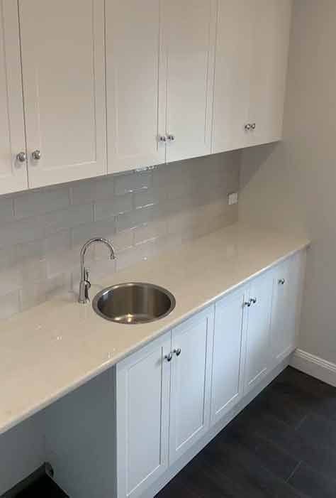 A kitchen with white cabinets and a stainless steel sink.