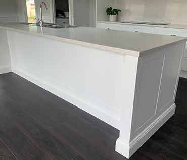 A kitchen with a large white island and a sink.