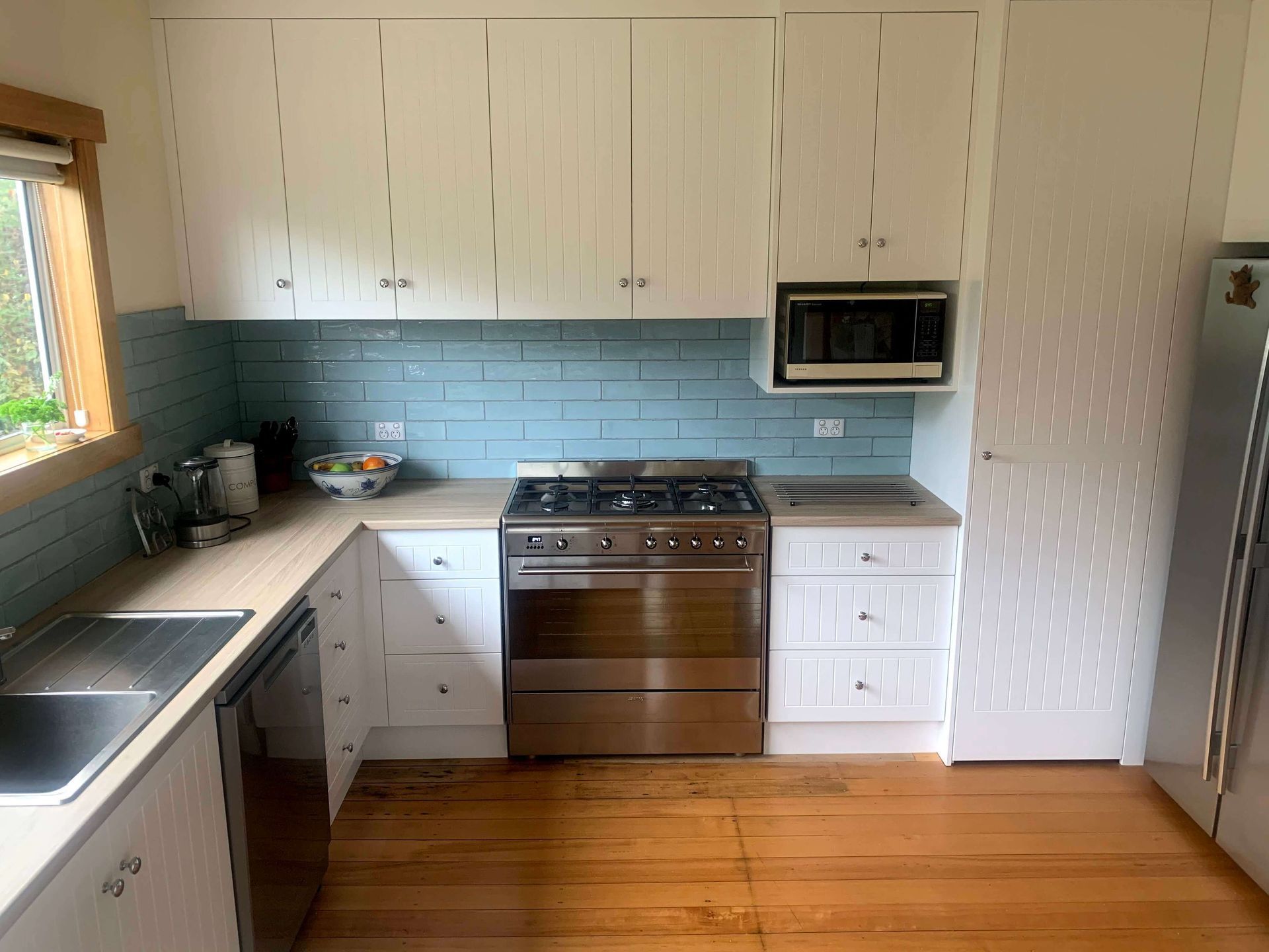 A kitchen with white cabinets , stainless steel appliances , a sink , and a microwave.