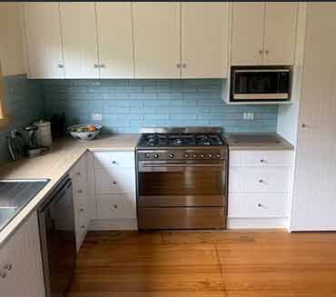A kitchen with stainless steel appliances and white cabinets.