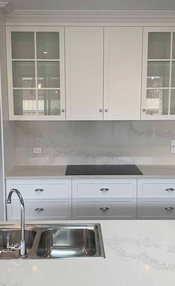 A kitchen with white cabinets, a sink , and a stove top oven.
