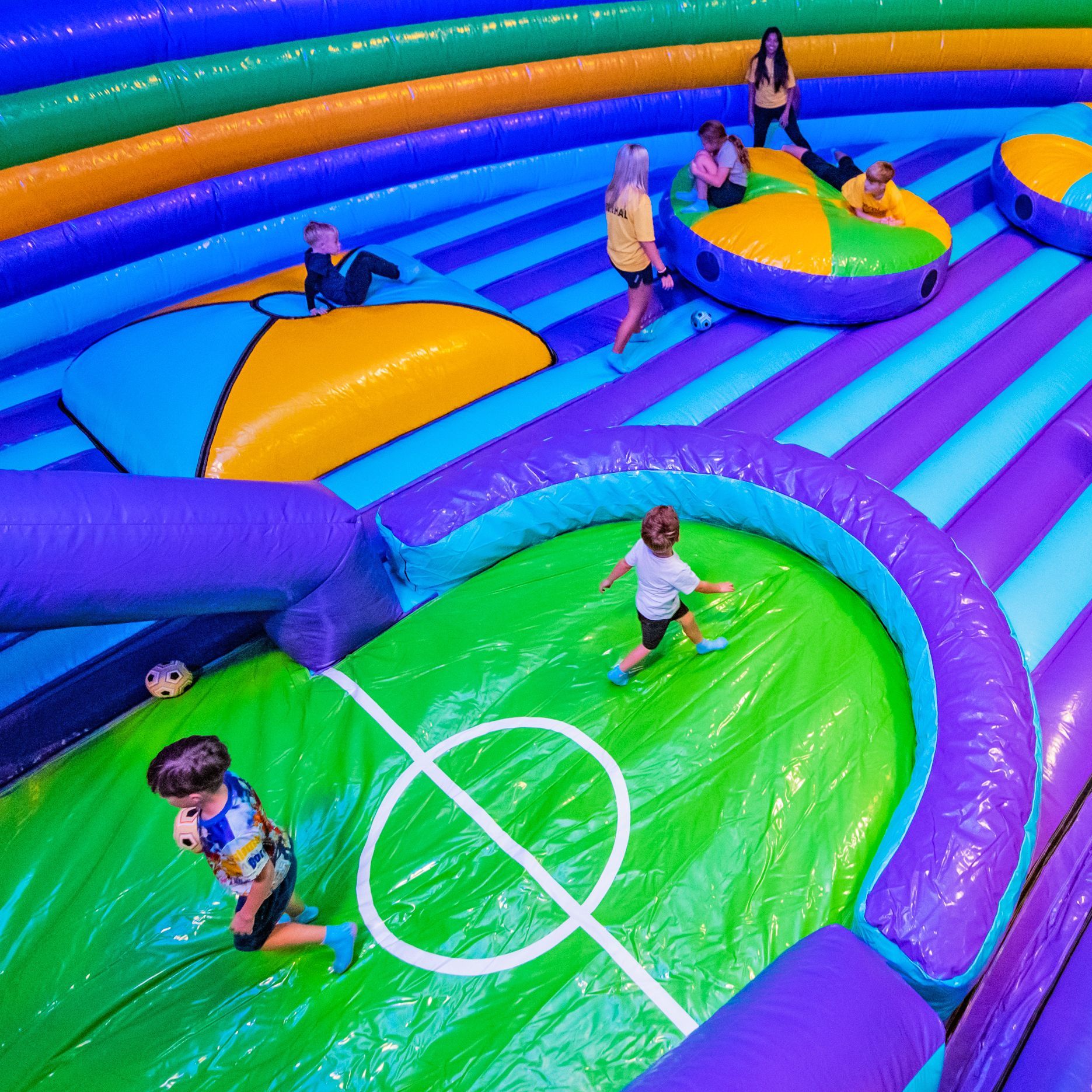 A group of children are playing on an inflatable soccer field.