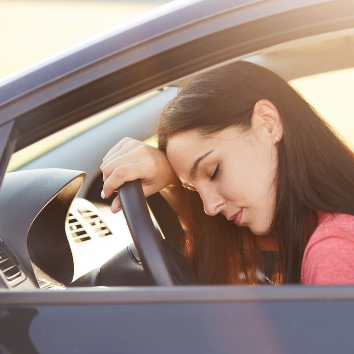 femme dormant au volant de sa voiture garée