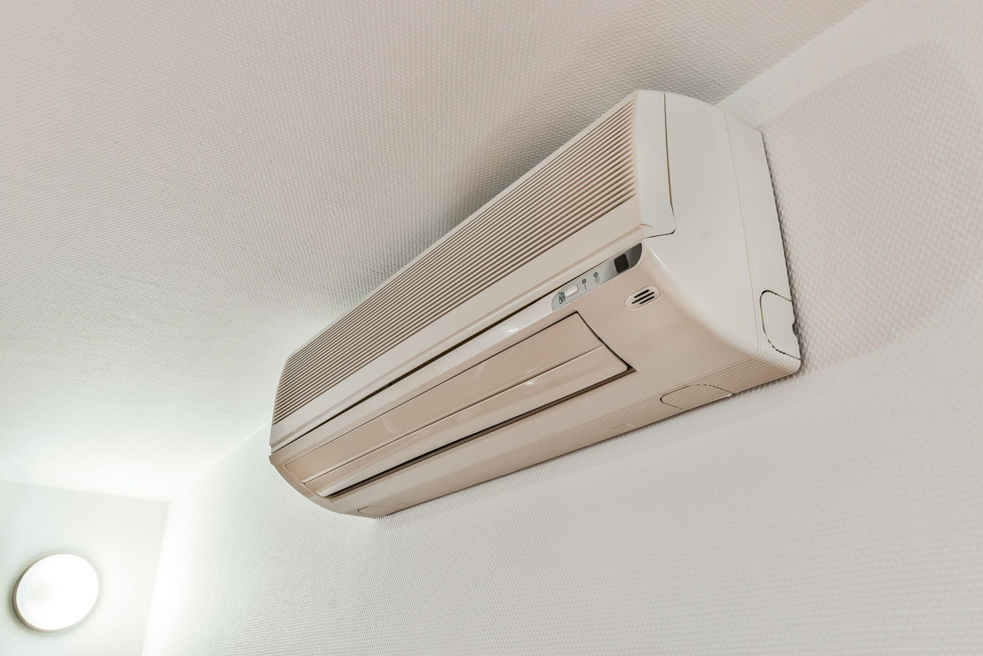 A wall-mounted, white air conditioning unit installed on a white wall.