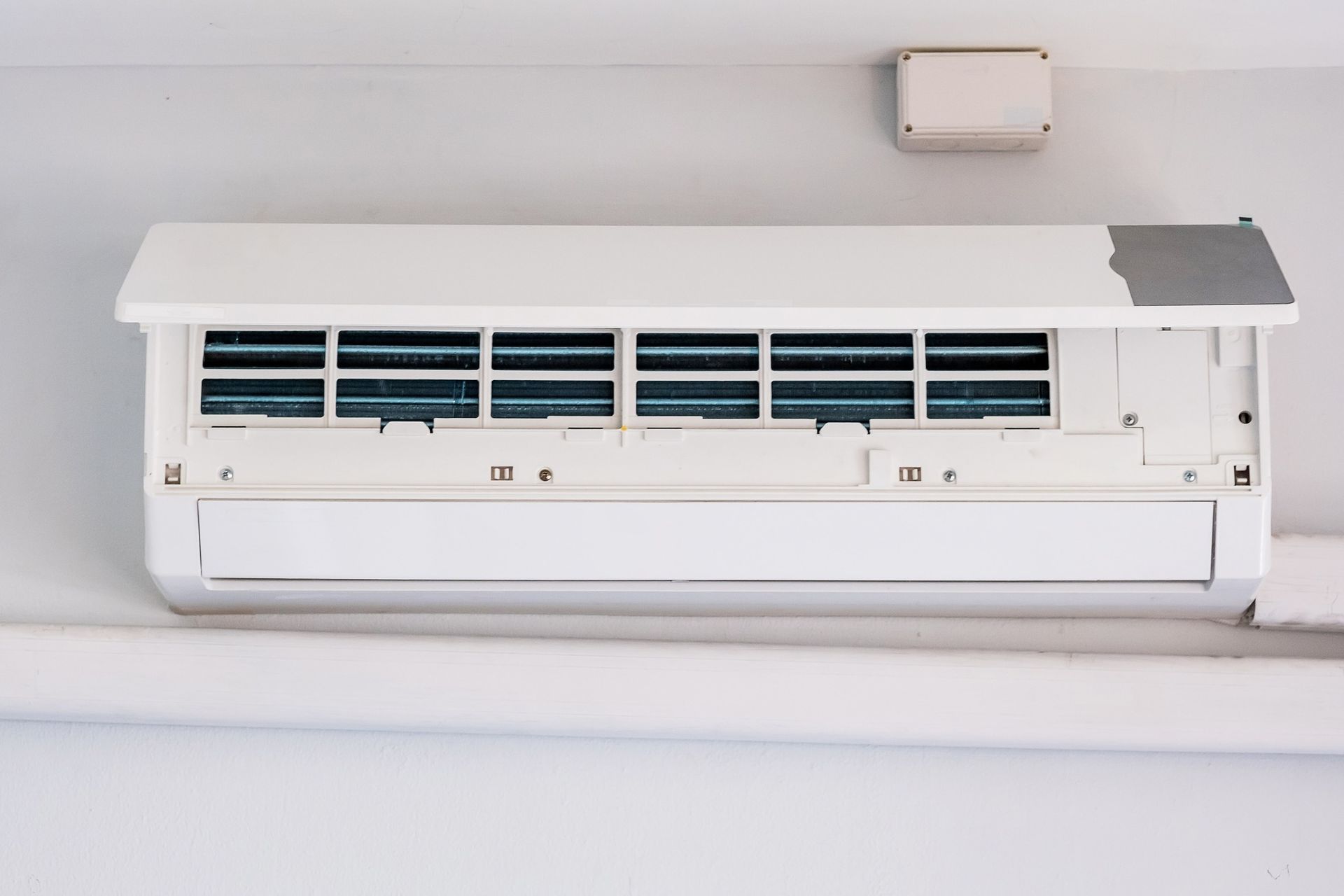 A white wall-mounted air conditioning unit with its front panel open to expose the internal filters and components.