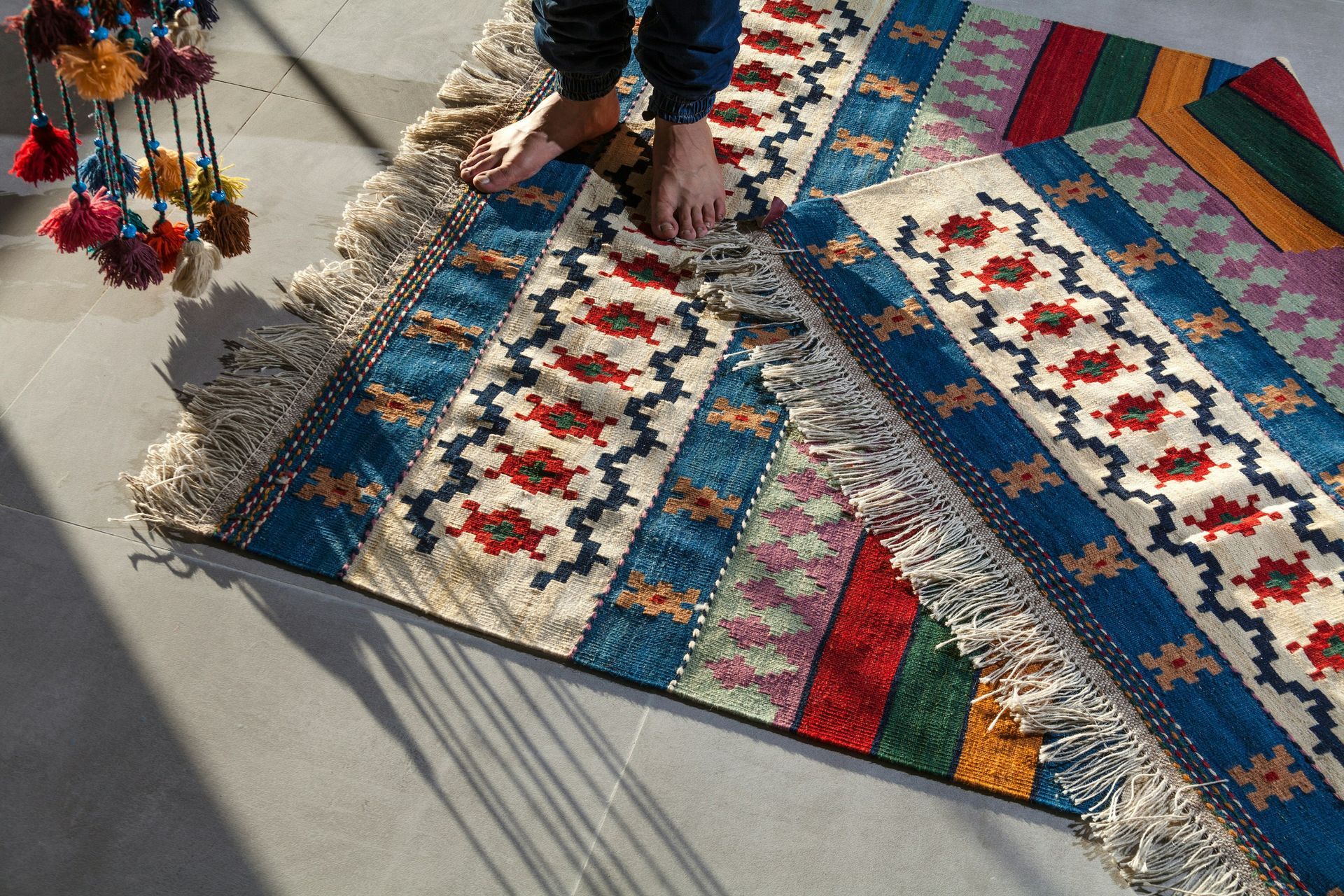 A person is standing on a colorful rug on the floor.