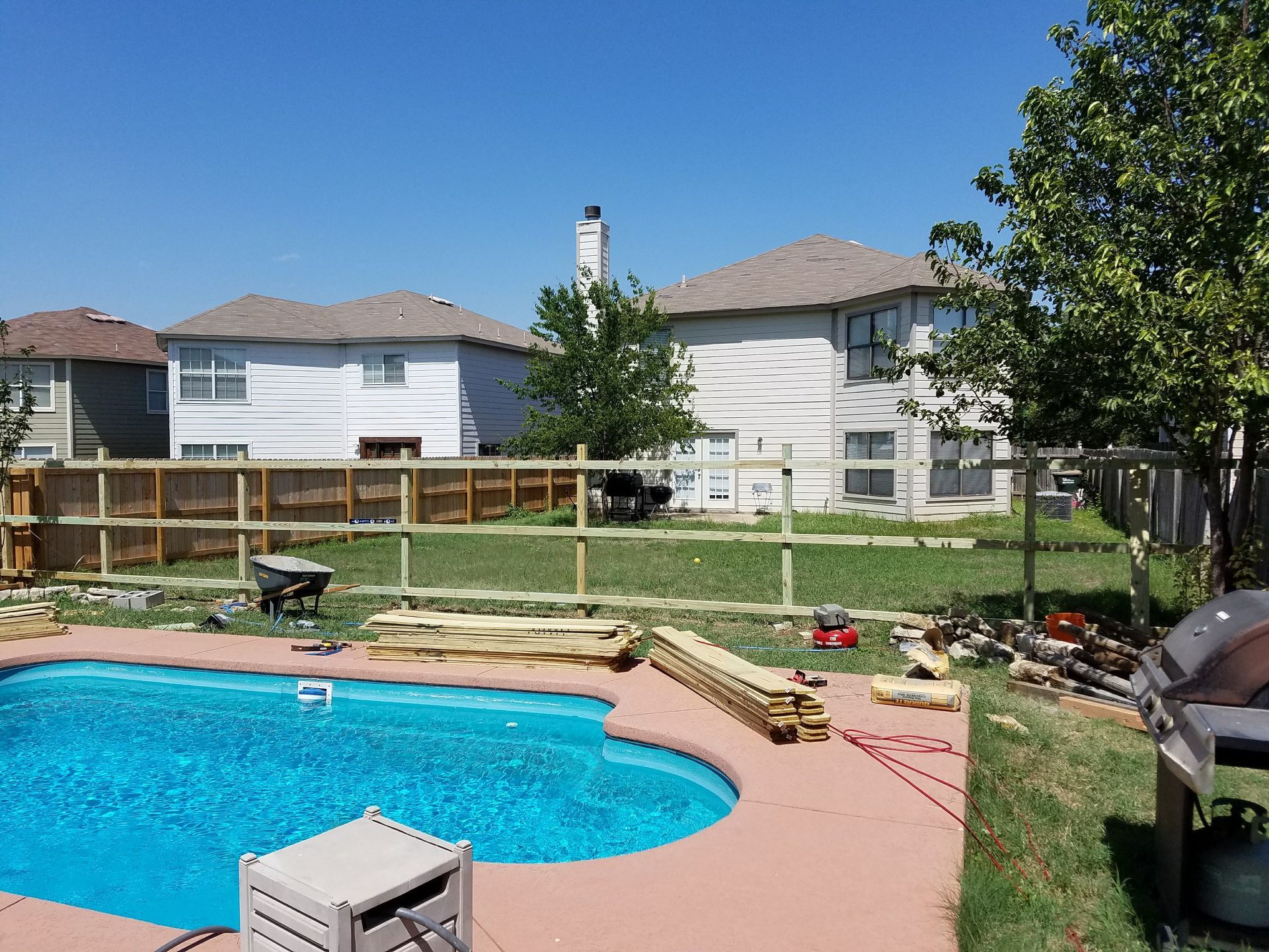 A backyard with a swimming pool and a wooden fence
