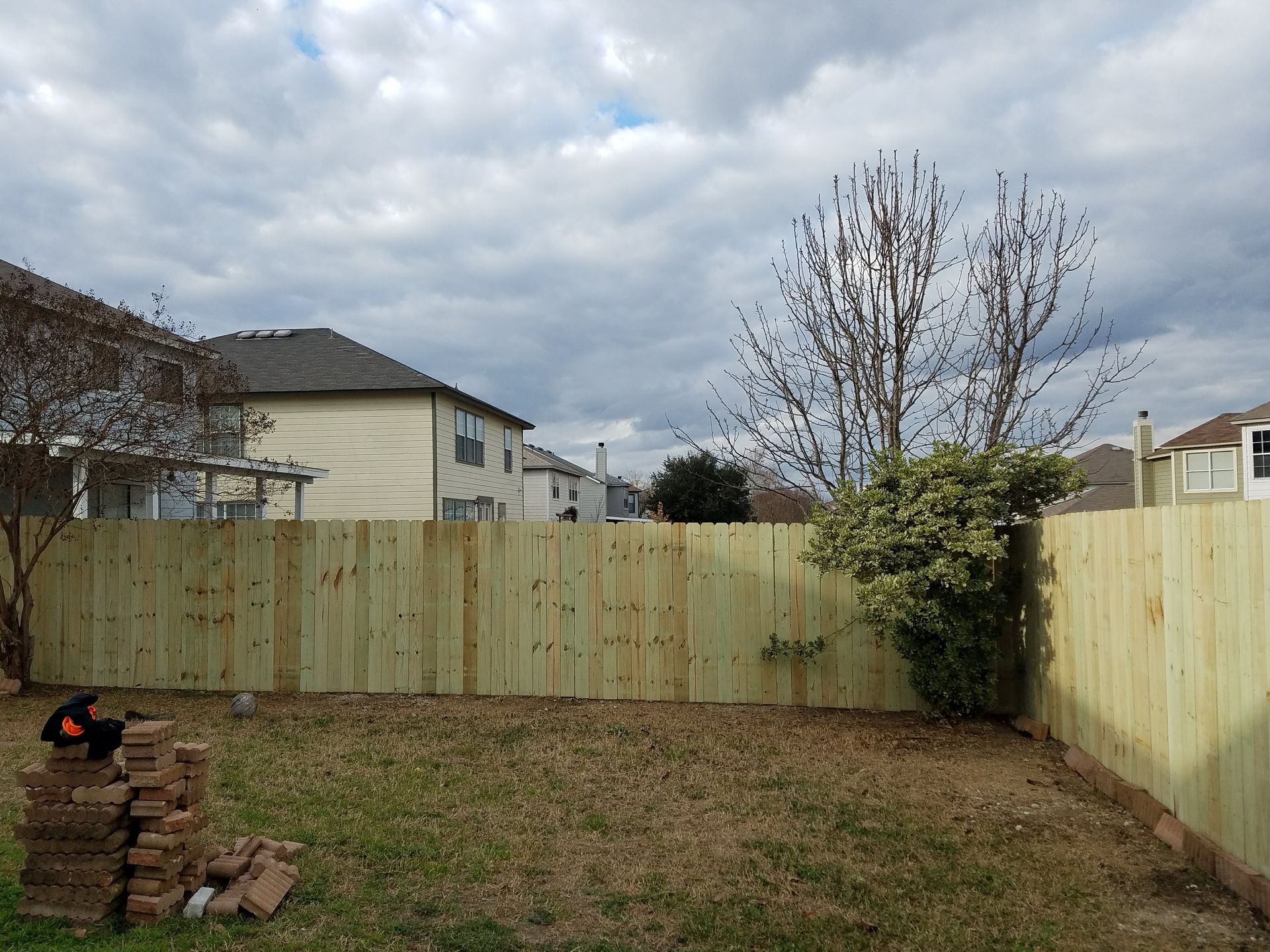 A backyard with a wooden fence and a stack of bricks