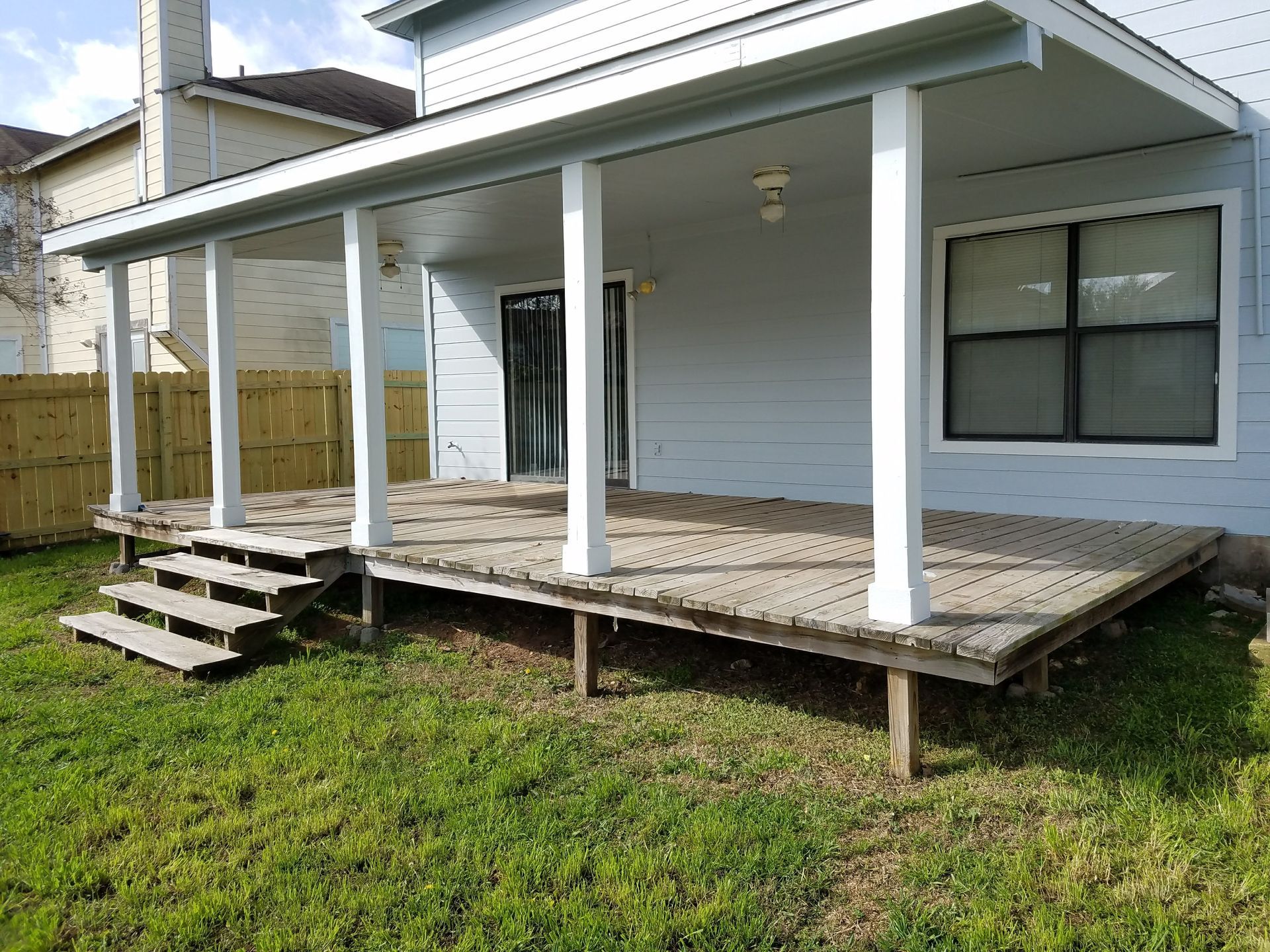 A house with a porch and stairs in the backyard.