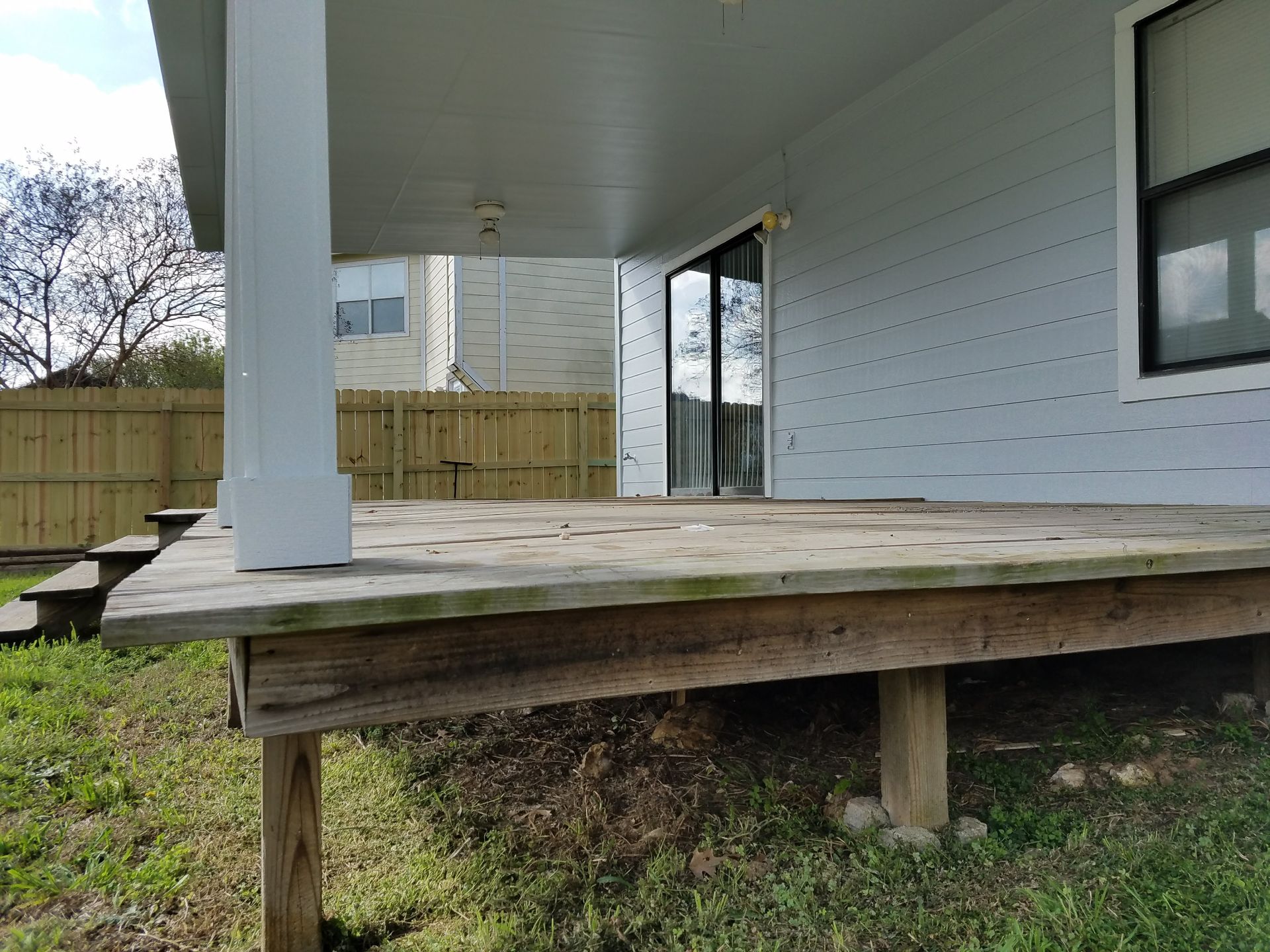 A white house with a wooden deck in front of it.