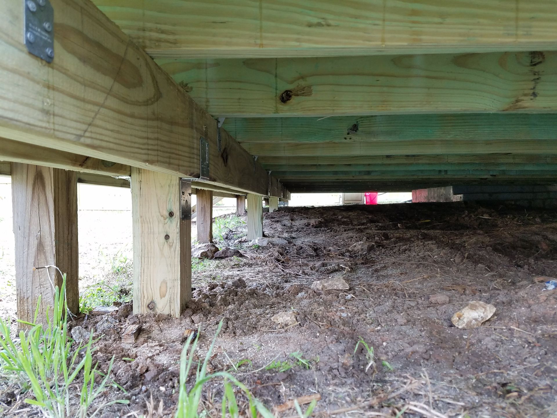 A wooden deck is being built under a house.