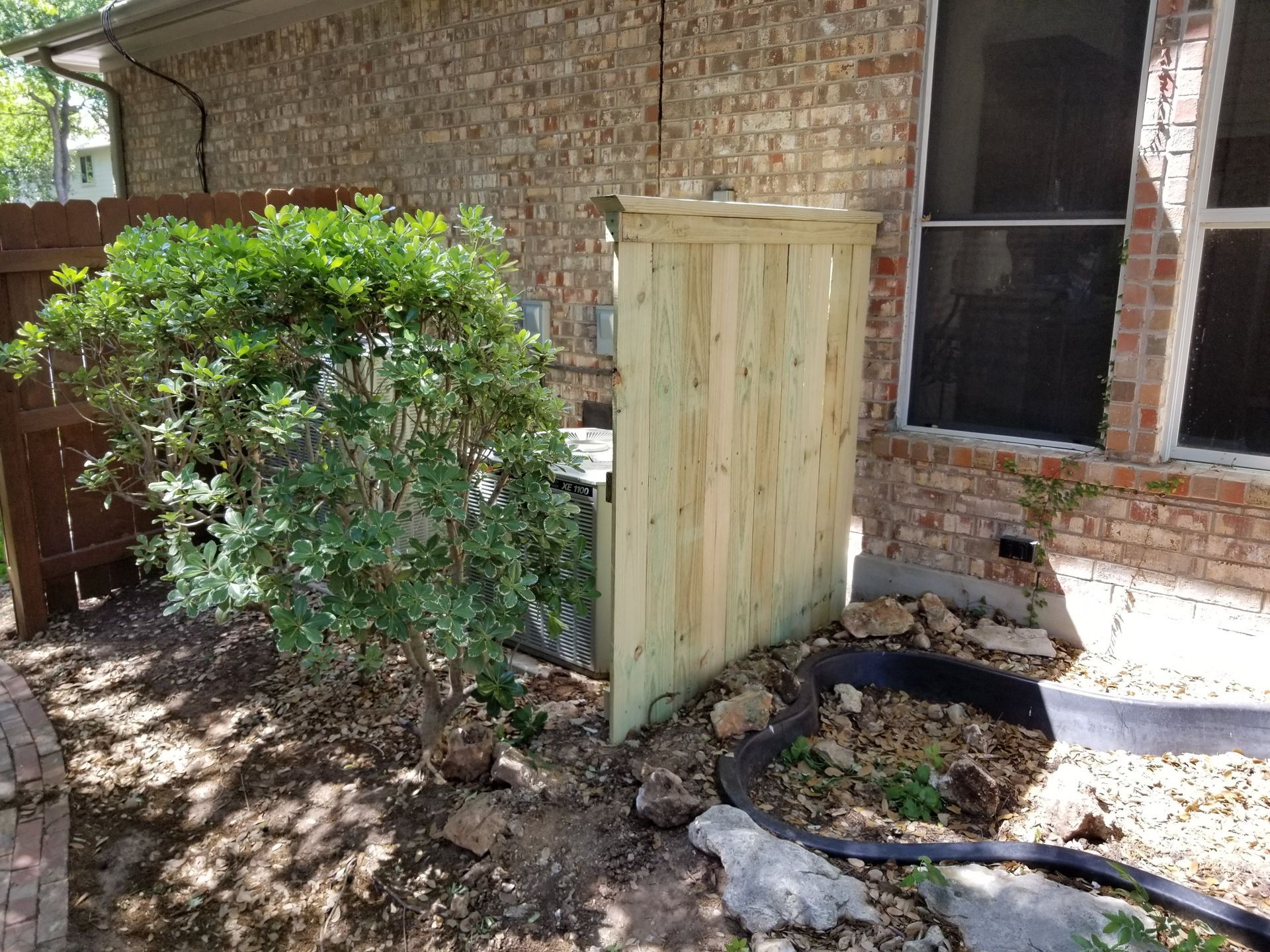 A wooden fence is sitting in front of a brick house.