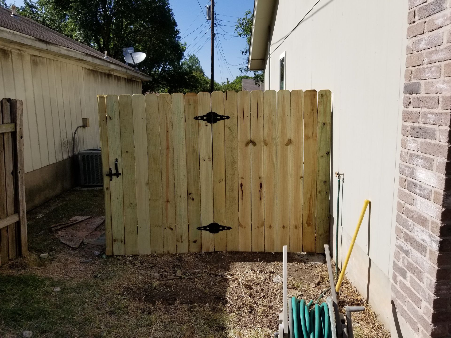 A wooden fence is in the backyard of a house.