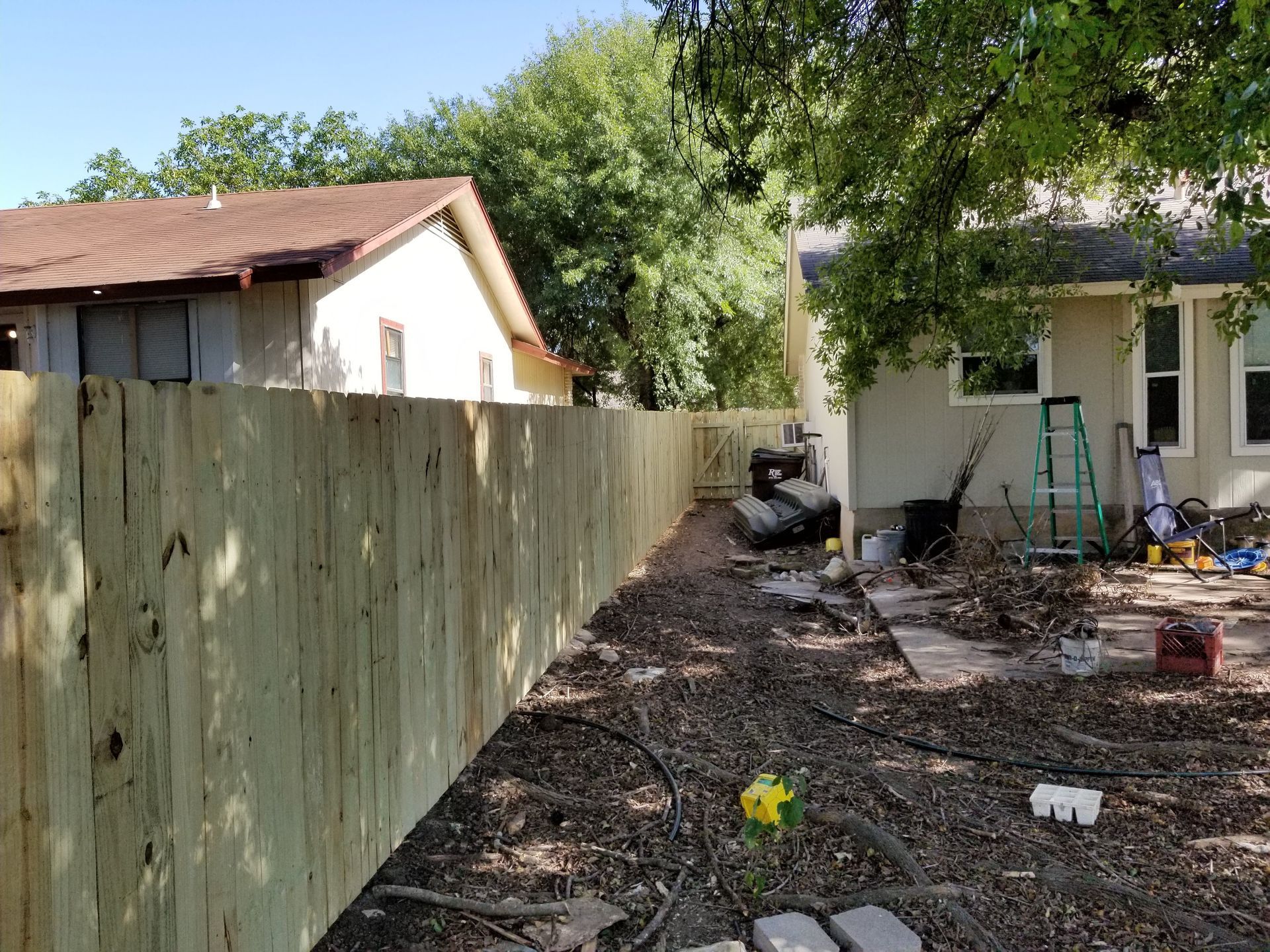 A wooden fence is being built in the backyard of a house.