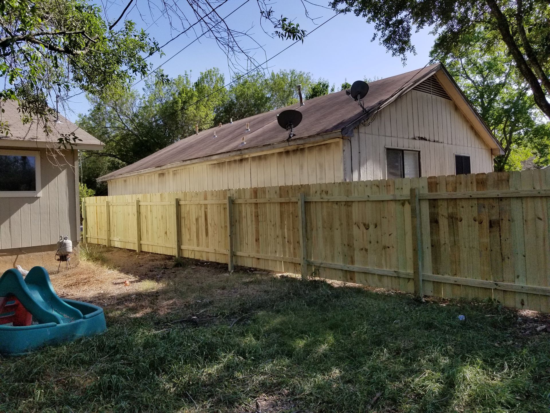 A wooden fence is in the backyard of a house.