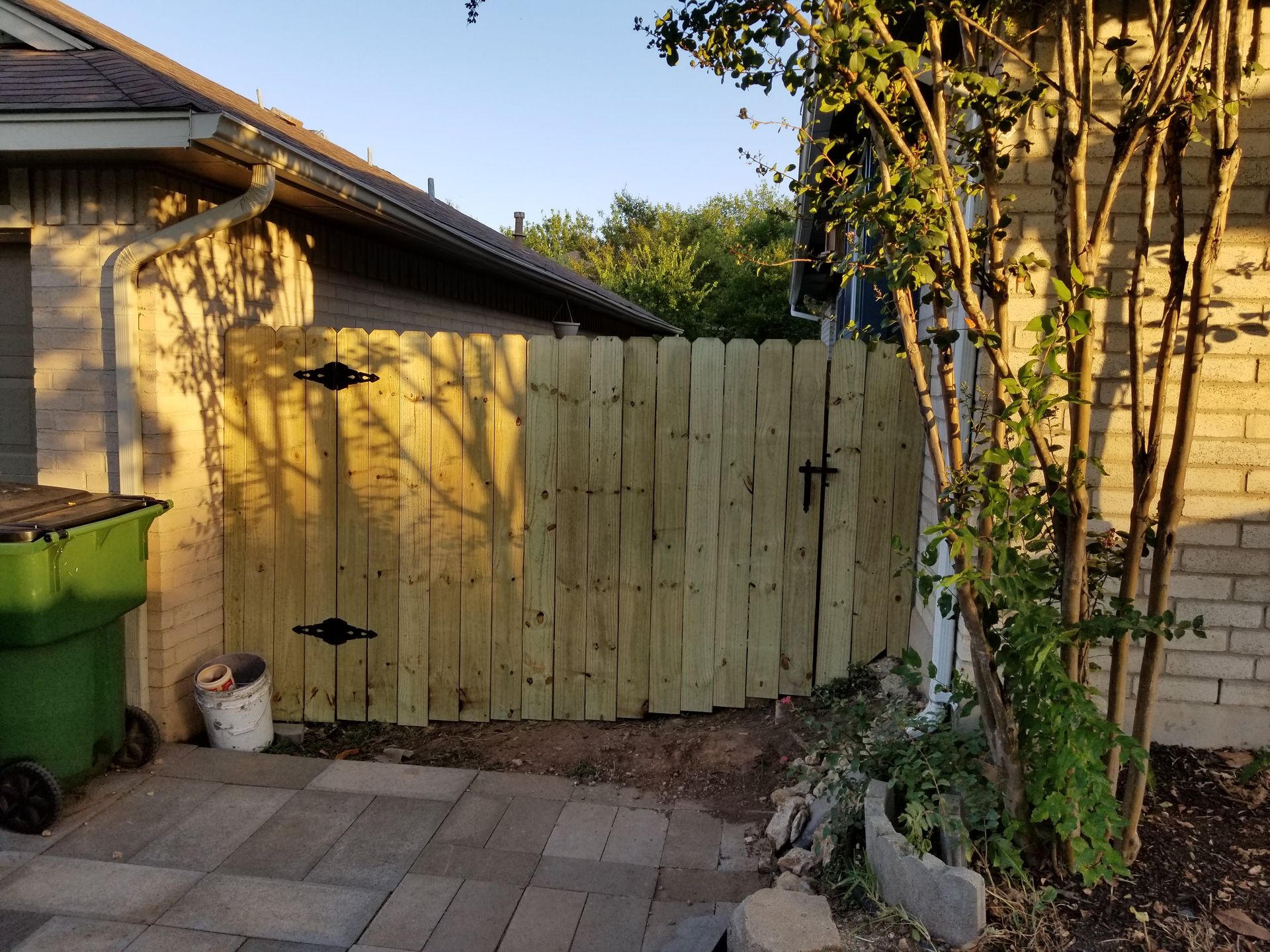 A wooden fence with a gate is in front of a house.