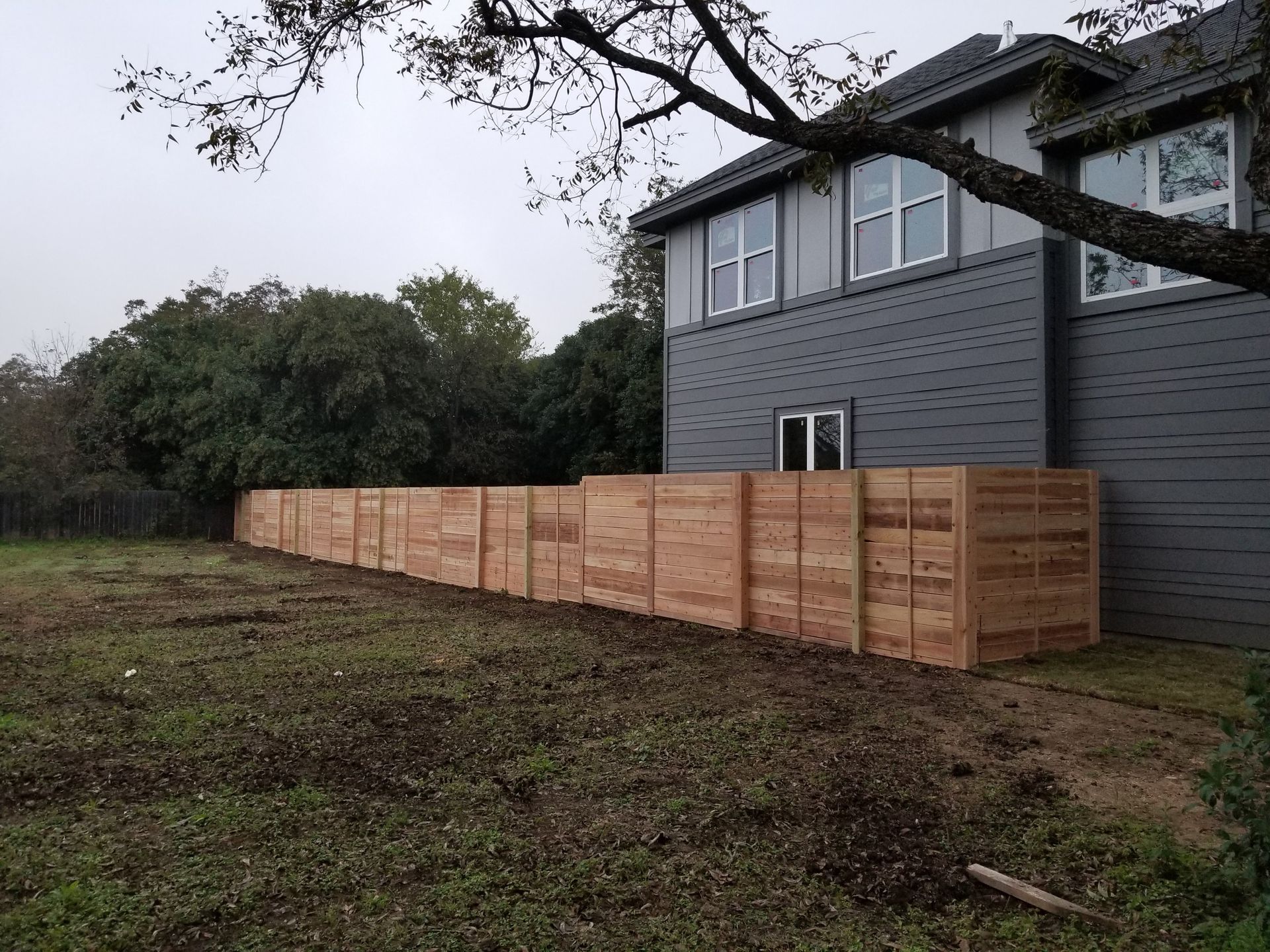 A wooden fence is sitting in front of a large house.