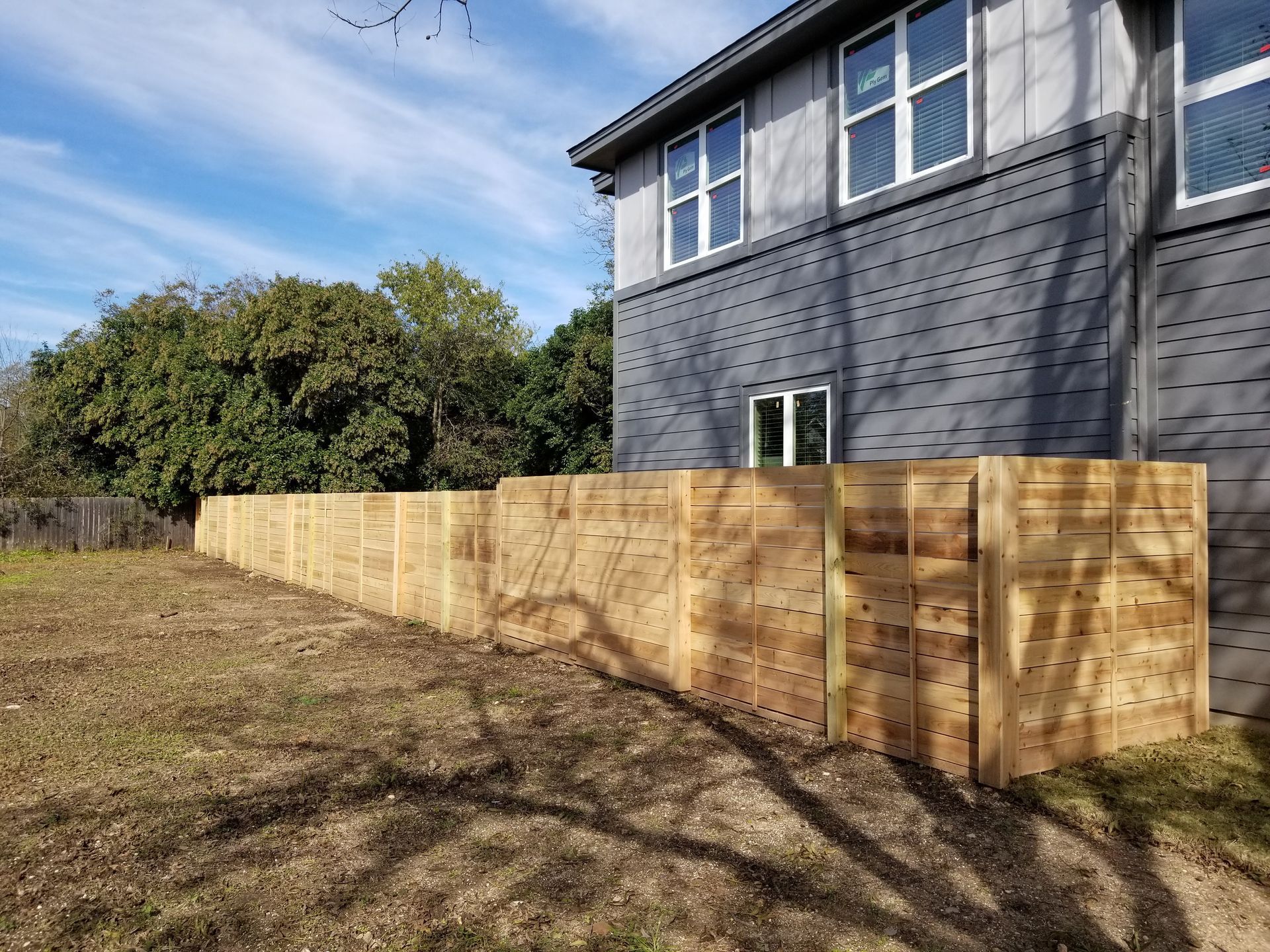 A wooden fence is in front of a large house.