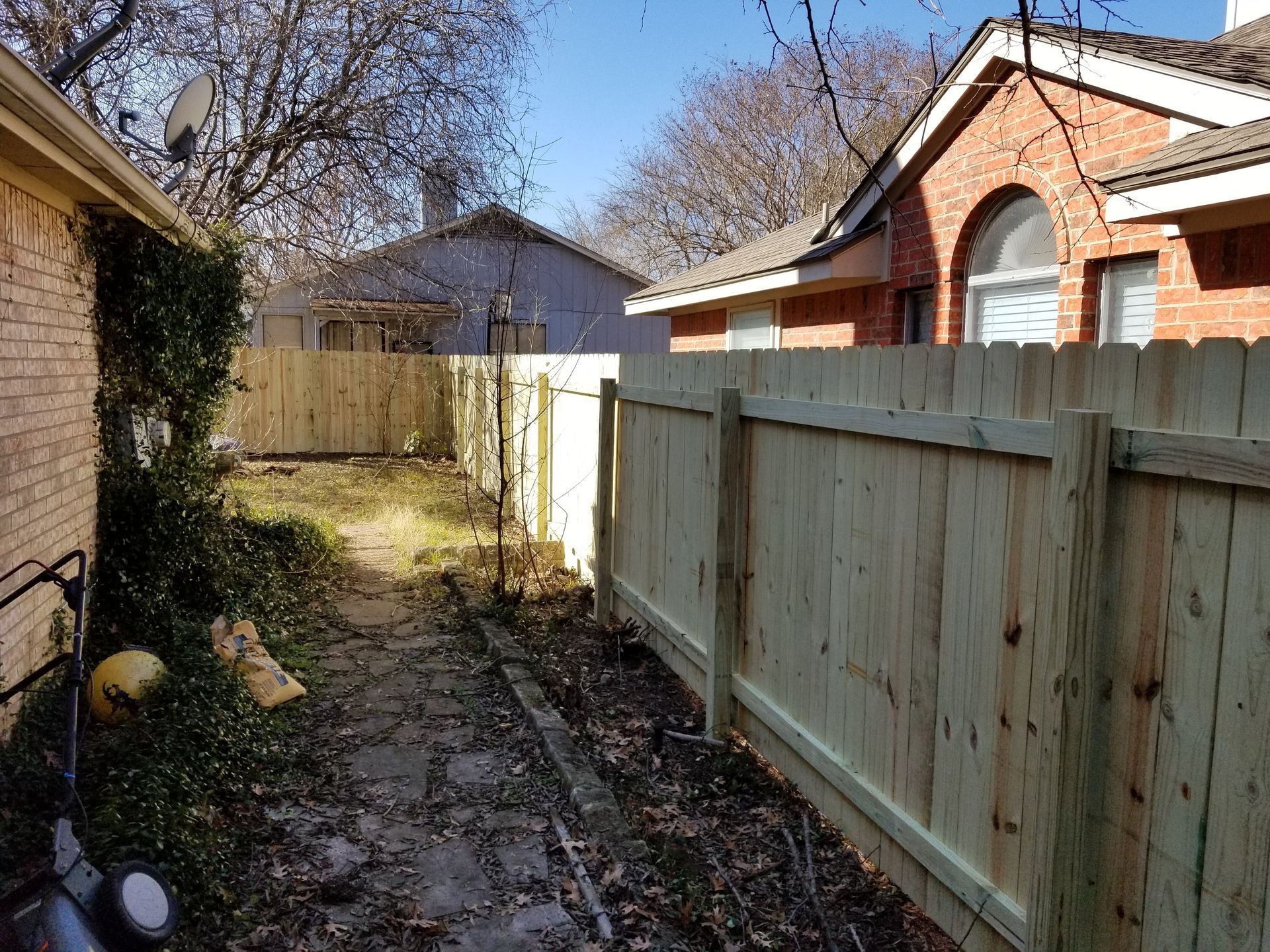 A wooden fence is in the backyard of a house.