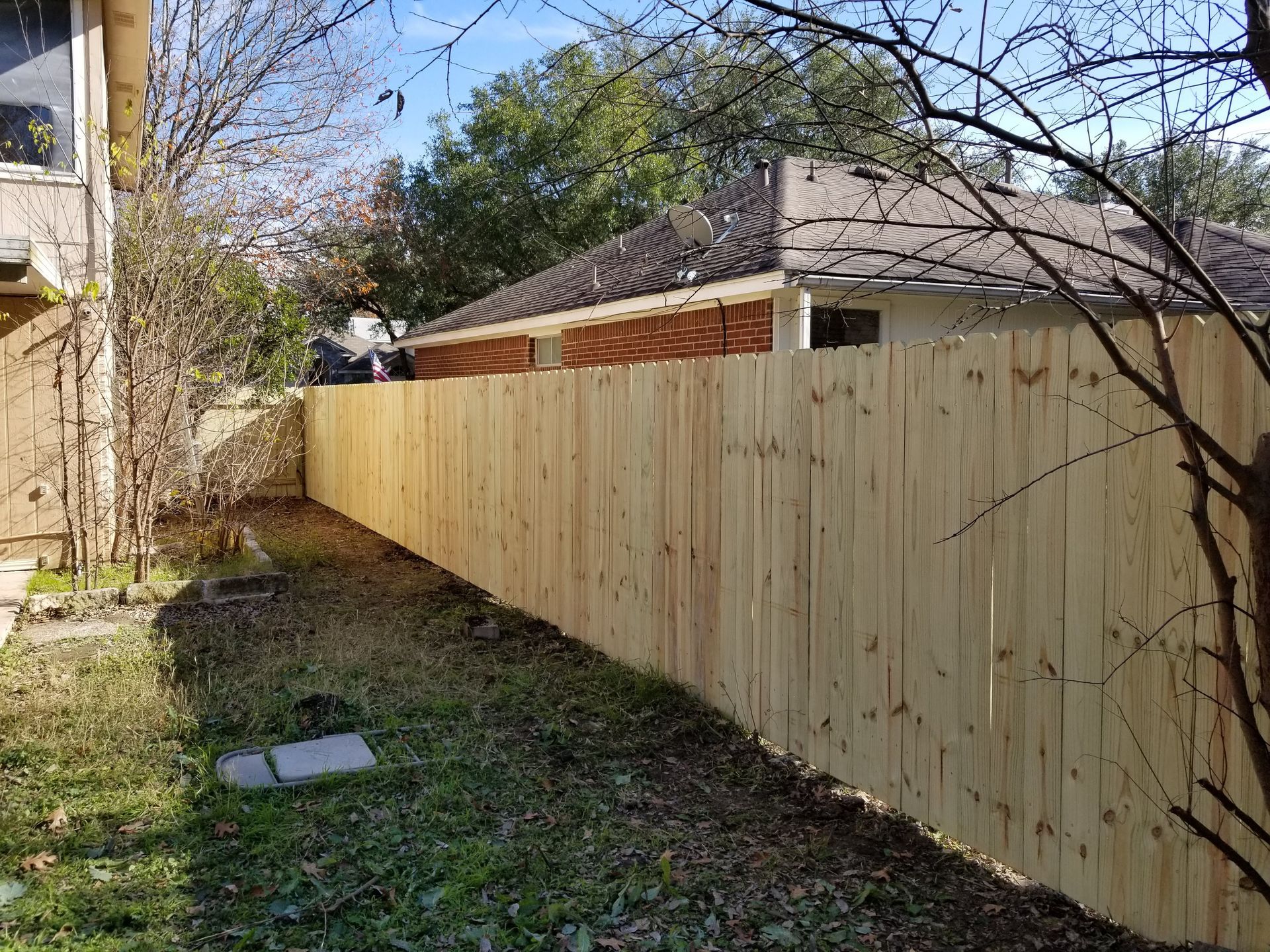 A wooden fence is in the backyard of a house.