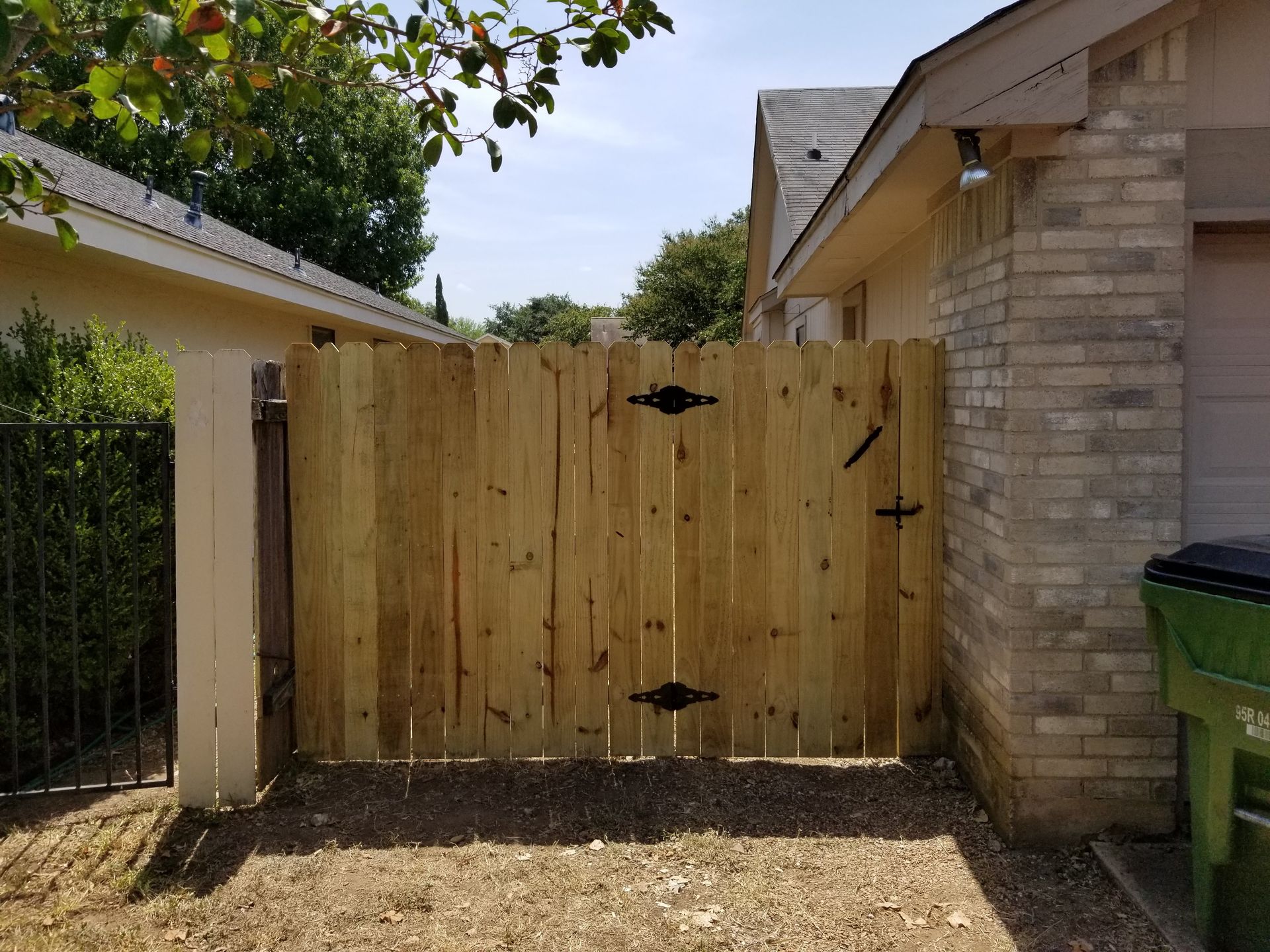 A wooden fence is sitting in front of a brick house.