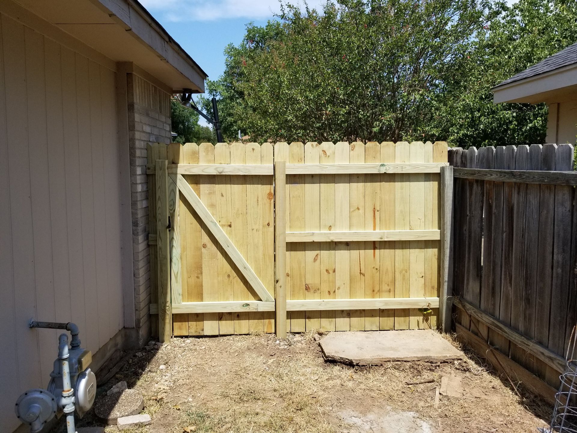 A wooden fence with a gate in the backyard of a house.