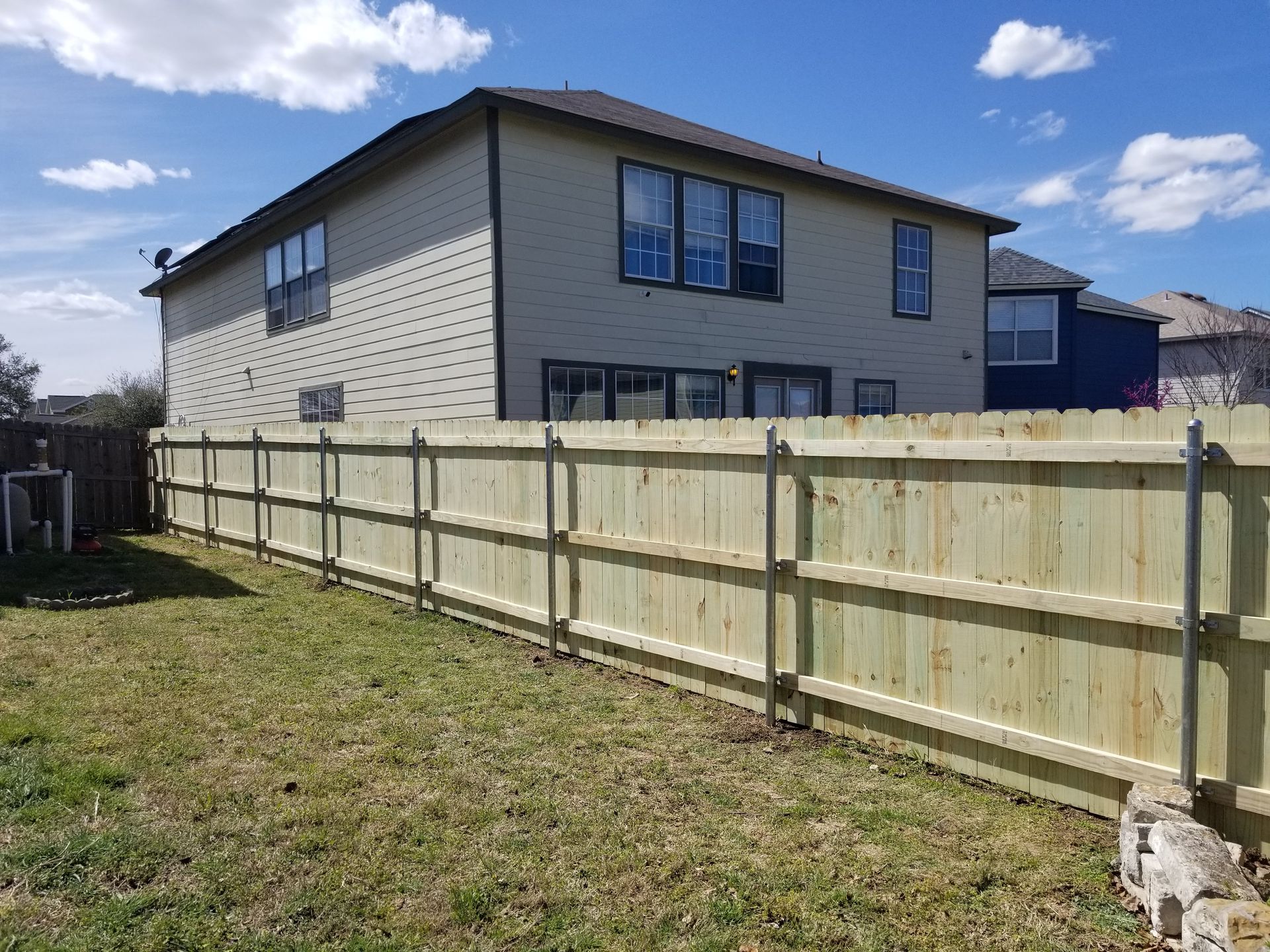 A wooden fence is in the backyard of a house.