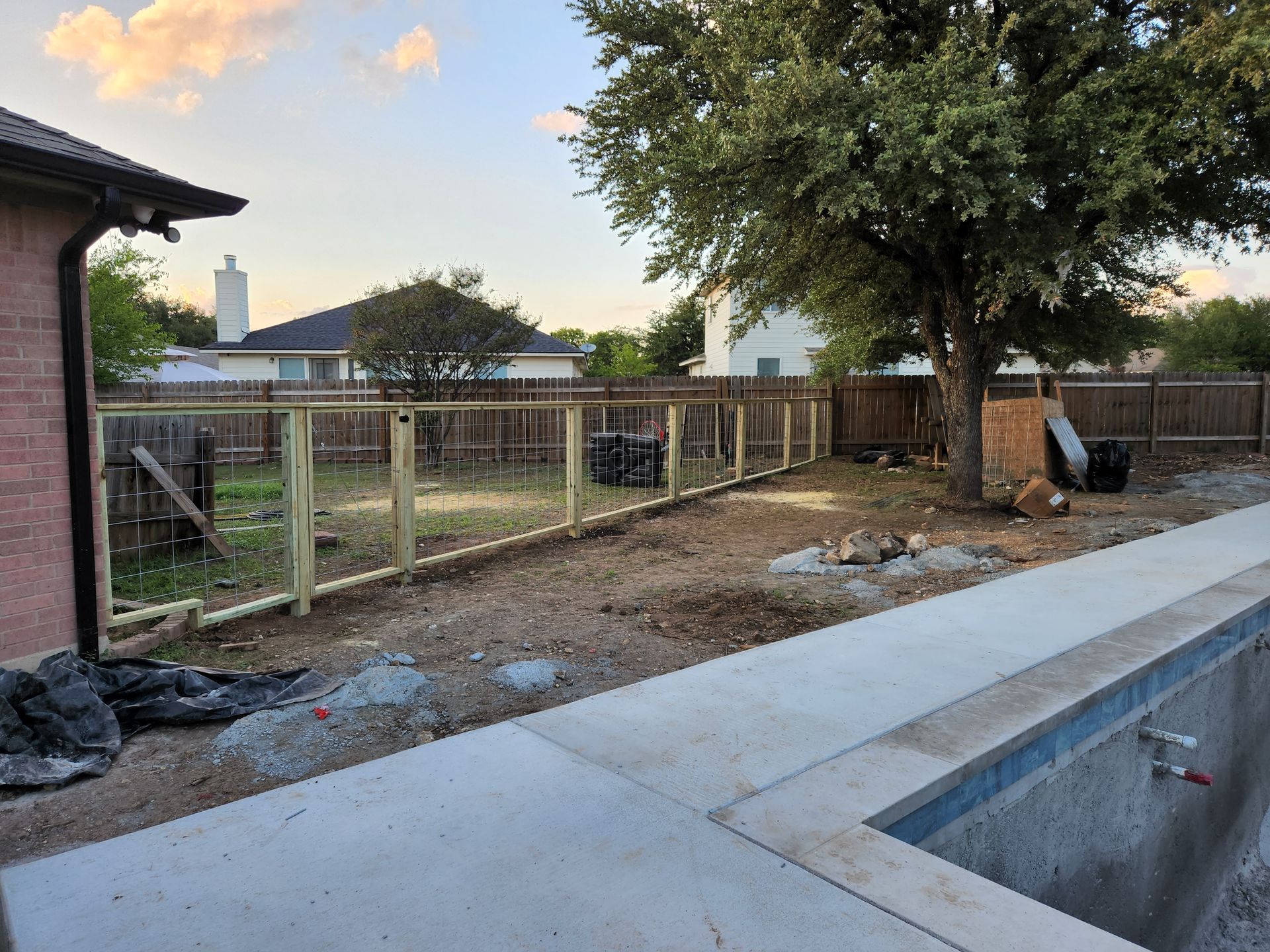 A wooden fence is being built in a backyard next to a pool.