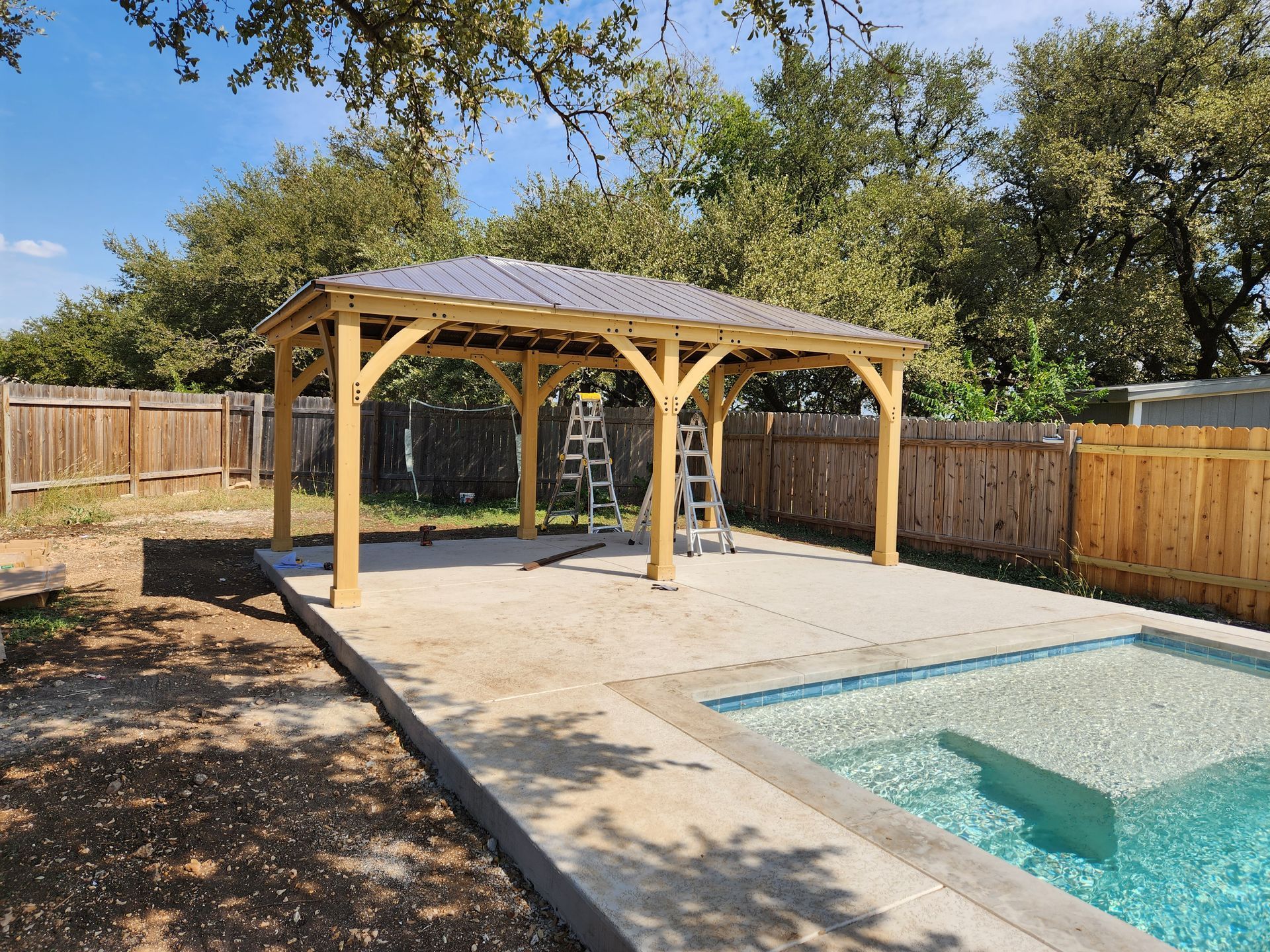 A wooden gazebo is being built next to a swimming pool.