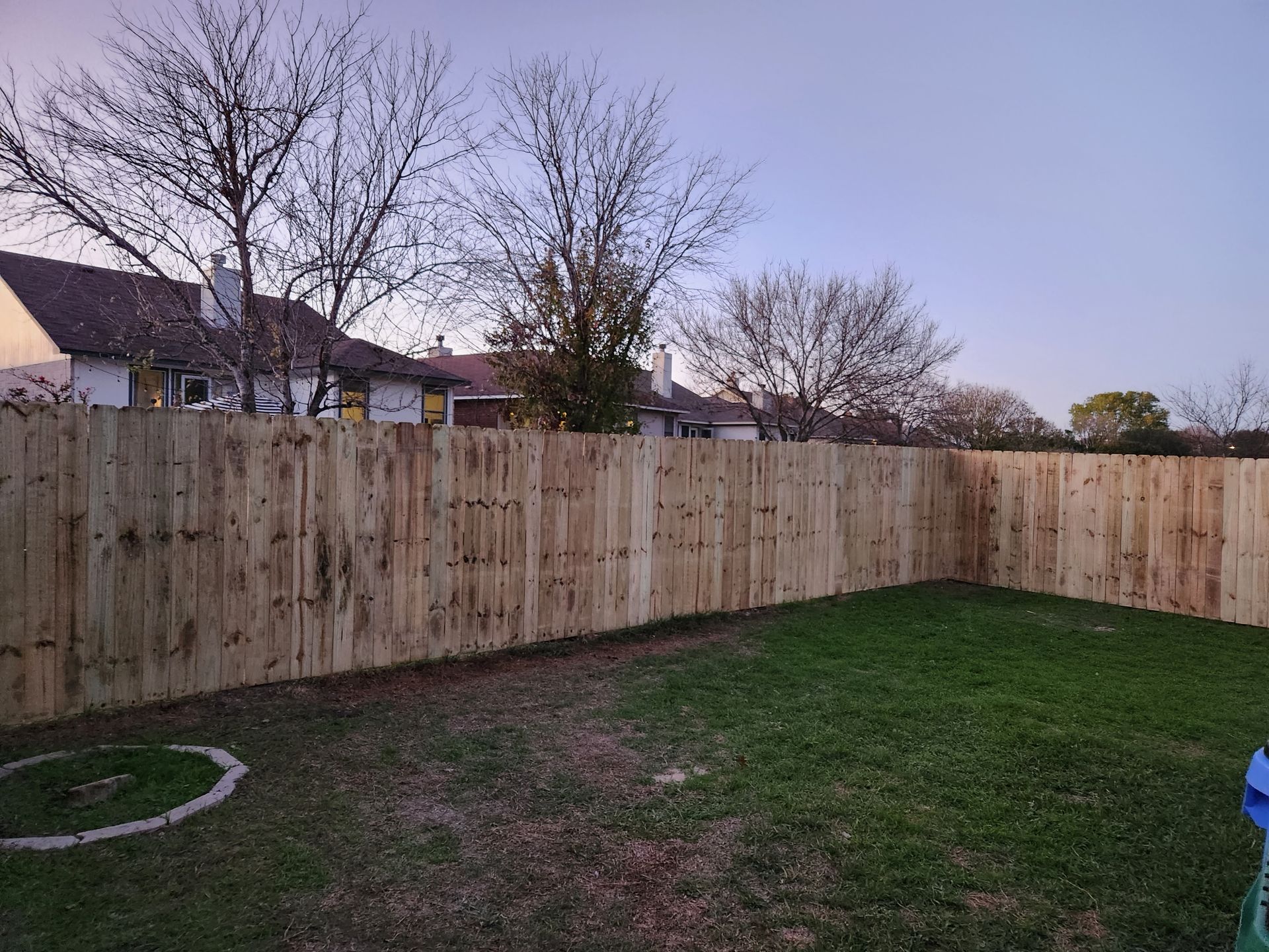 A wooden fence is in the backyard of a house.
