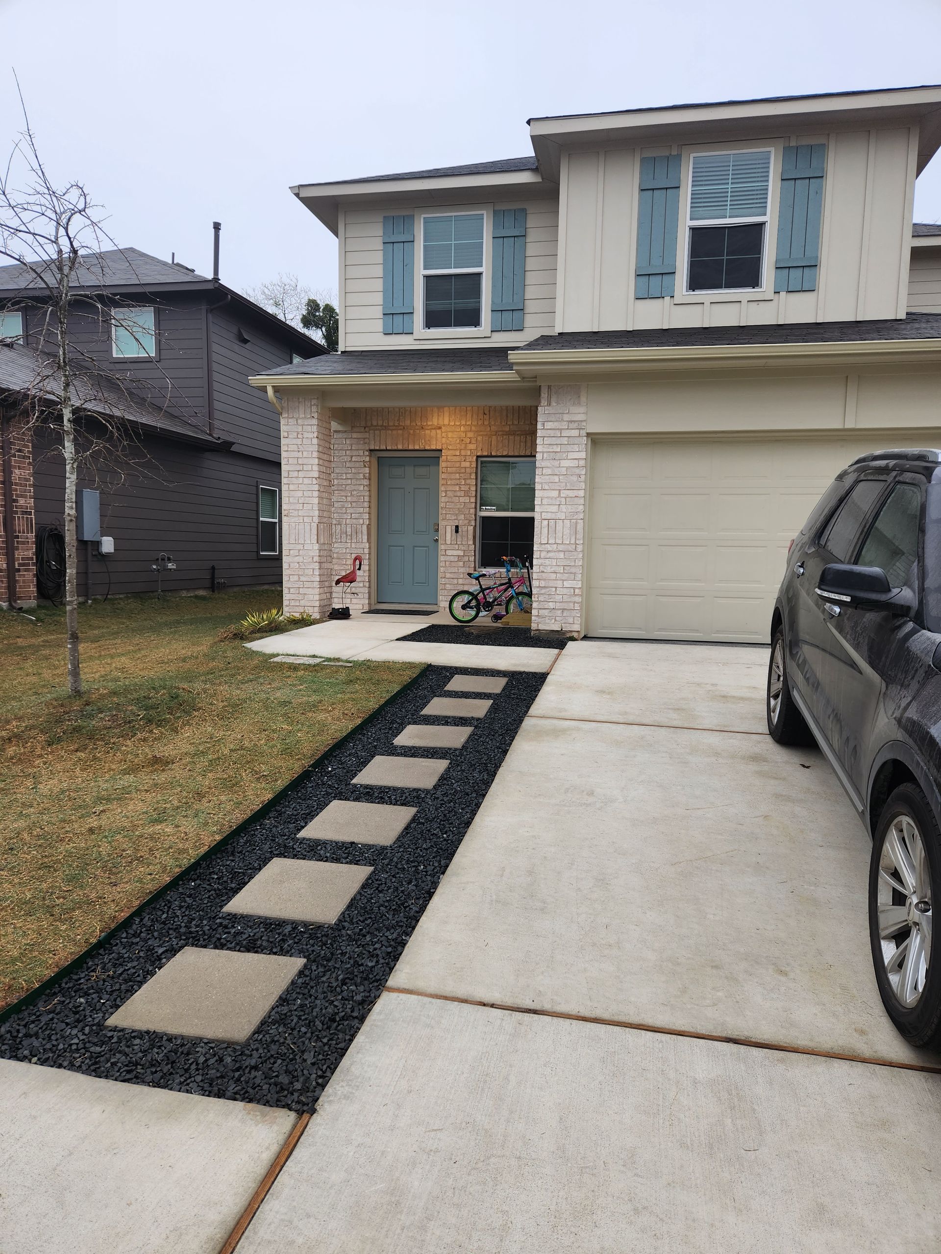 A car is parked in front of a house with blue shutters