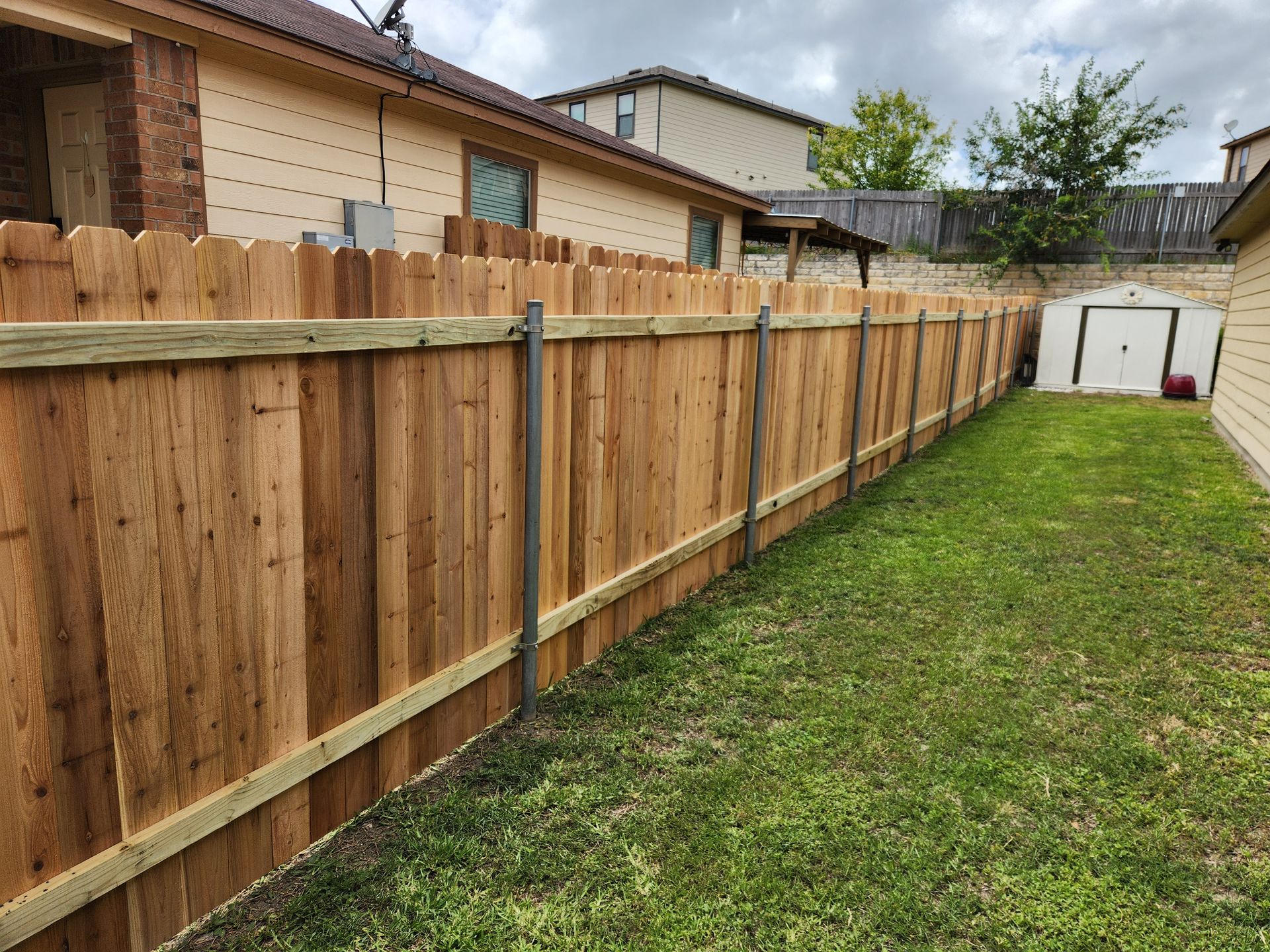A wooden fence is in the backyard of a house.
