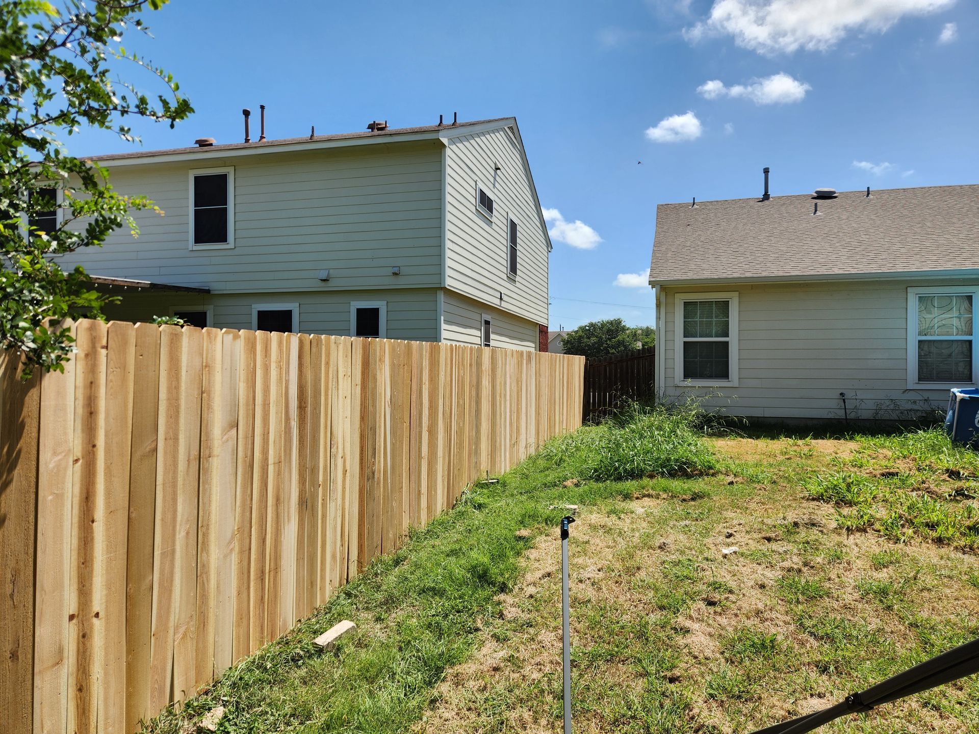 A wooden fence is in the backyard of a house.