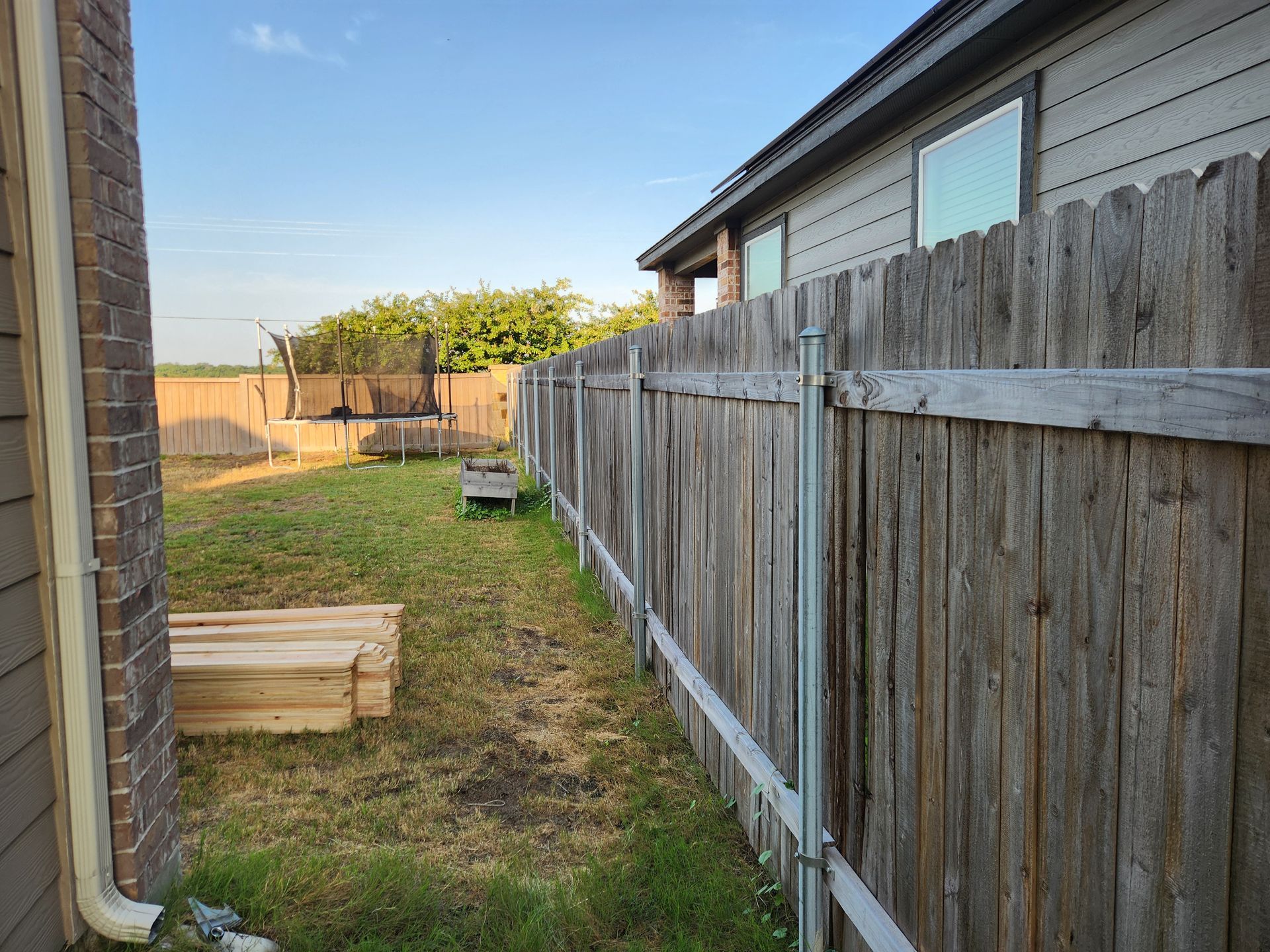 A wooden fence is in the backyard of a house.