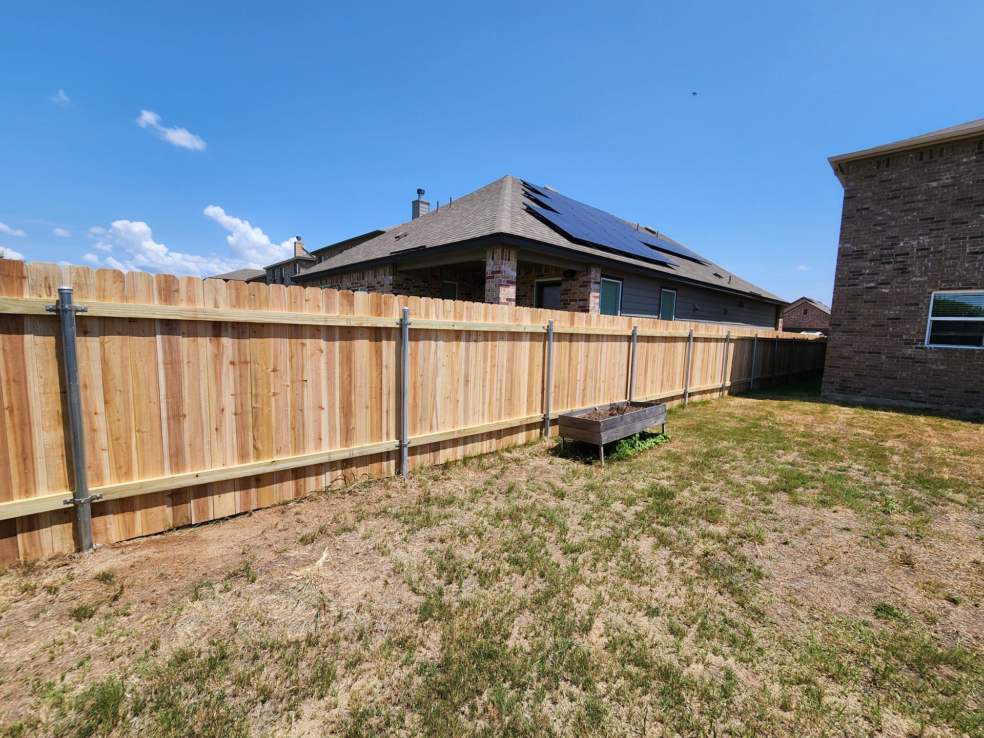 There is a wooden fence in the backyard of a house.