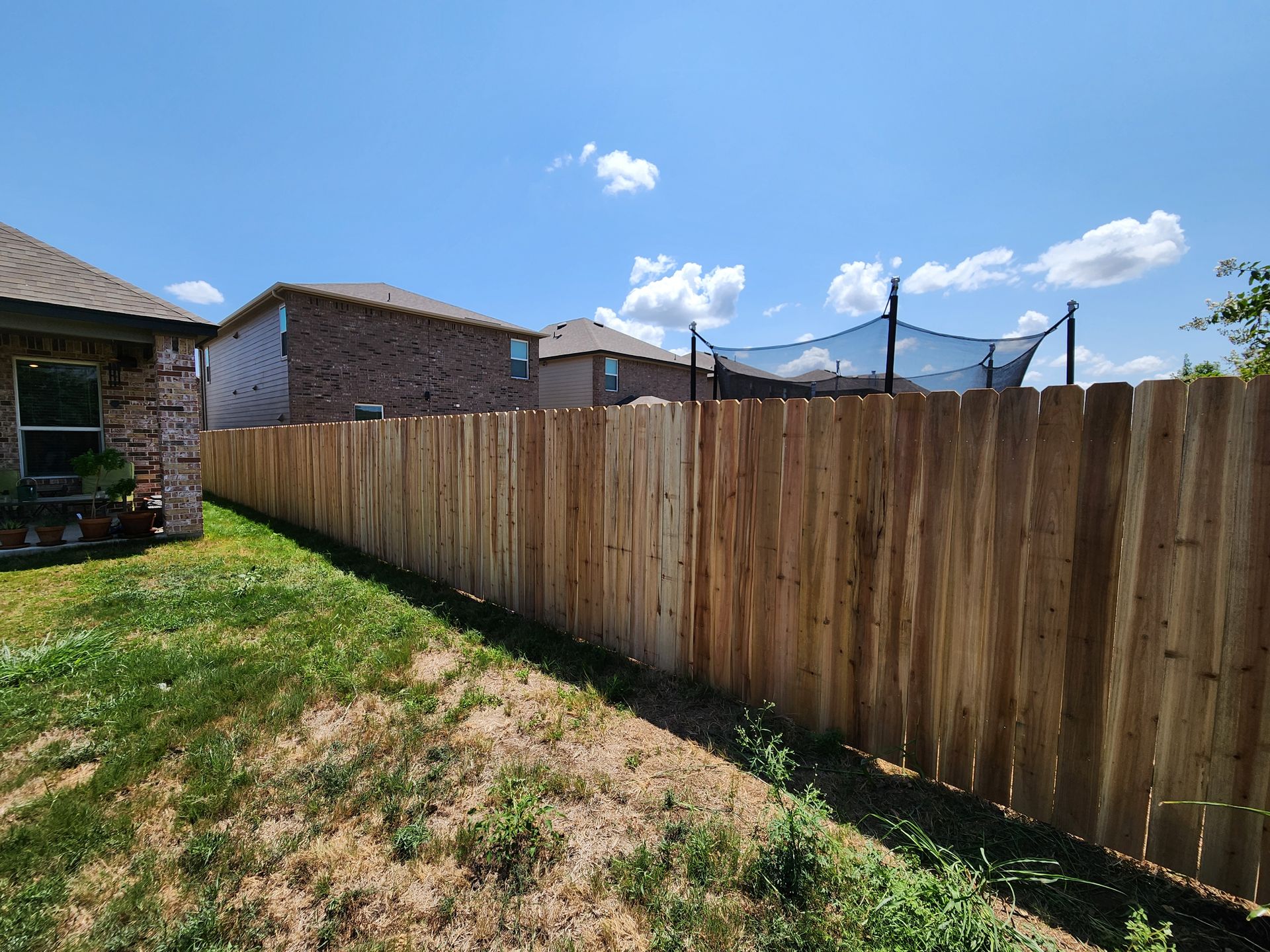 A wooden fence is in the backyard of a house.
